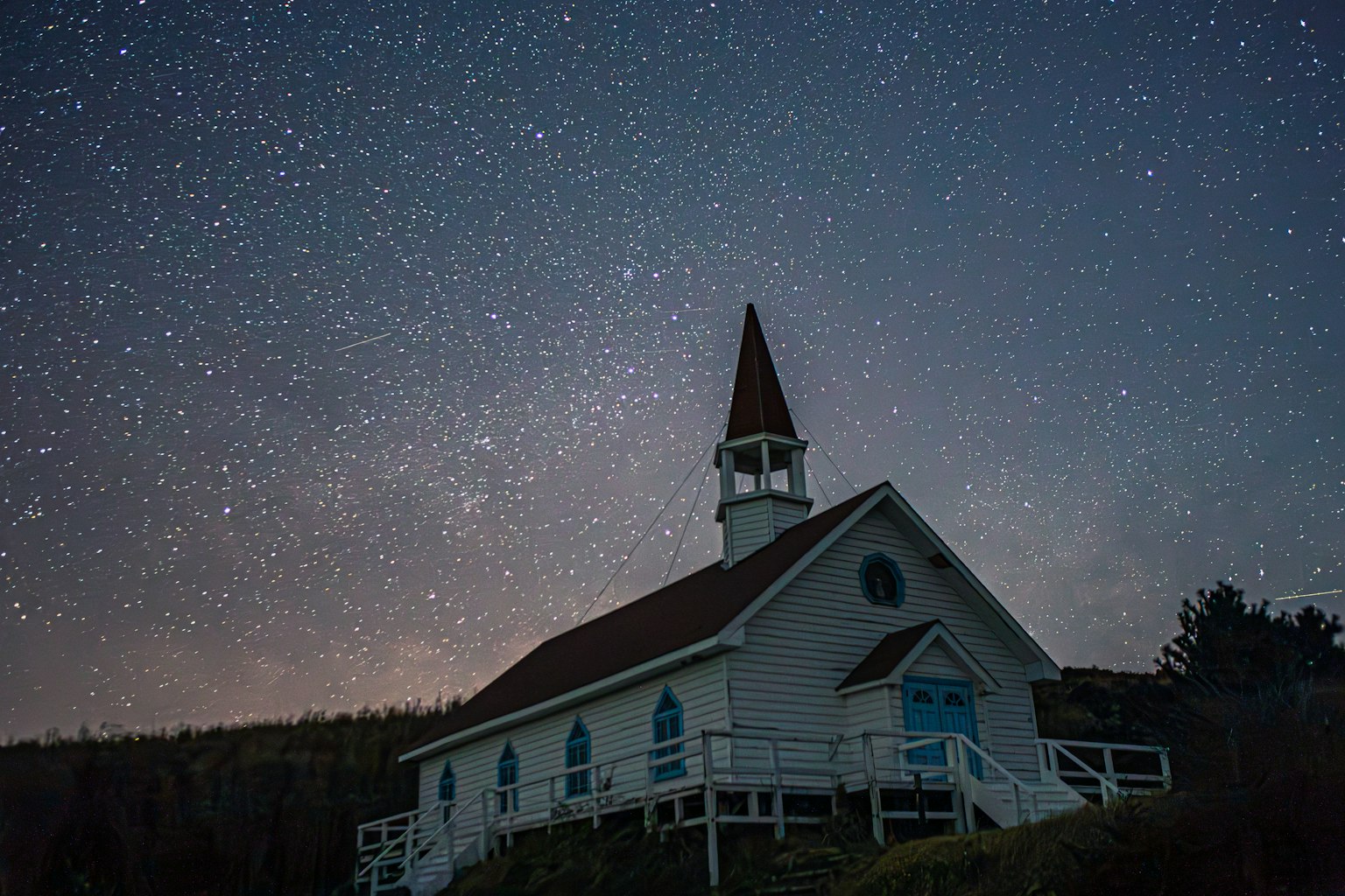Iglesia blanca con un campanario bajo un cielo estrellado