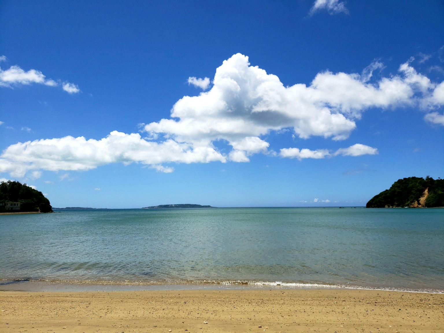 Pemandangan pantai dengan langit biru dan awan putih berbulu