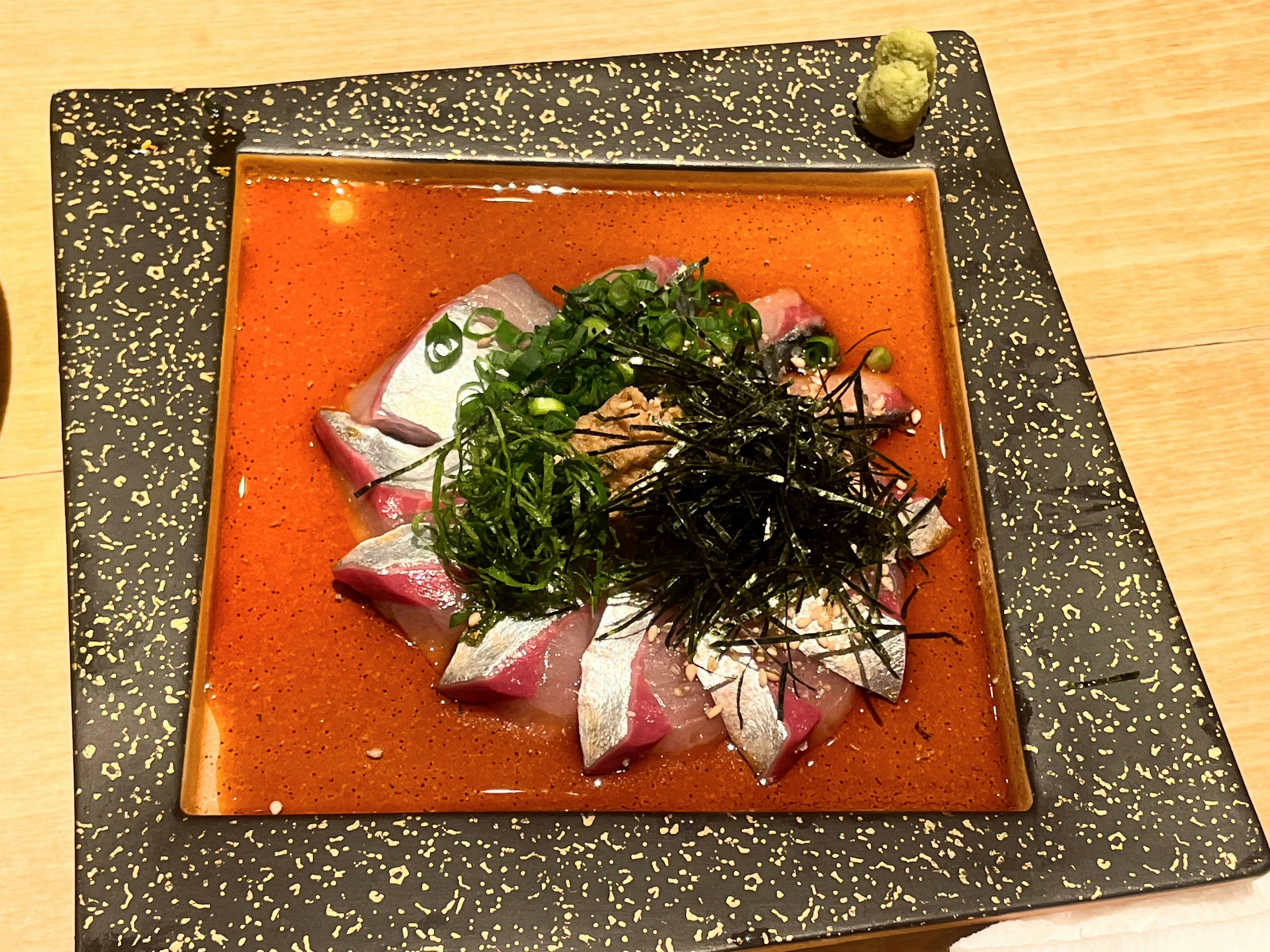 赤いソースの上に盛られた刺身と刻み海藻の前菜