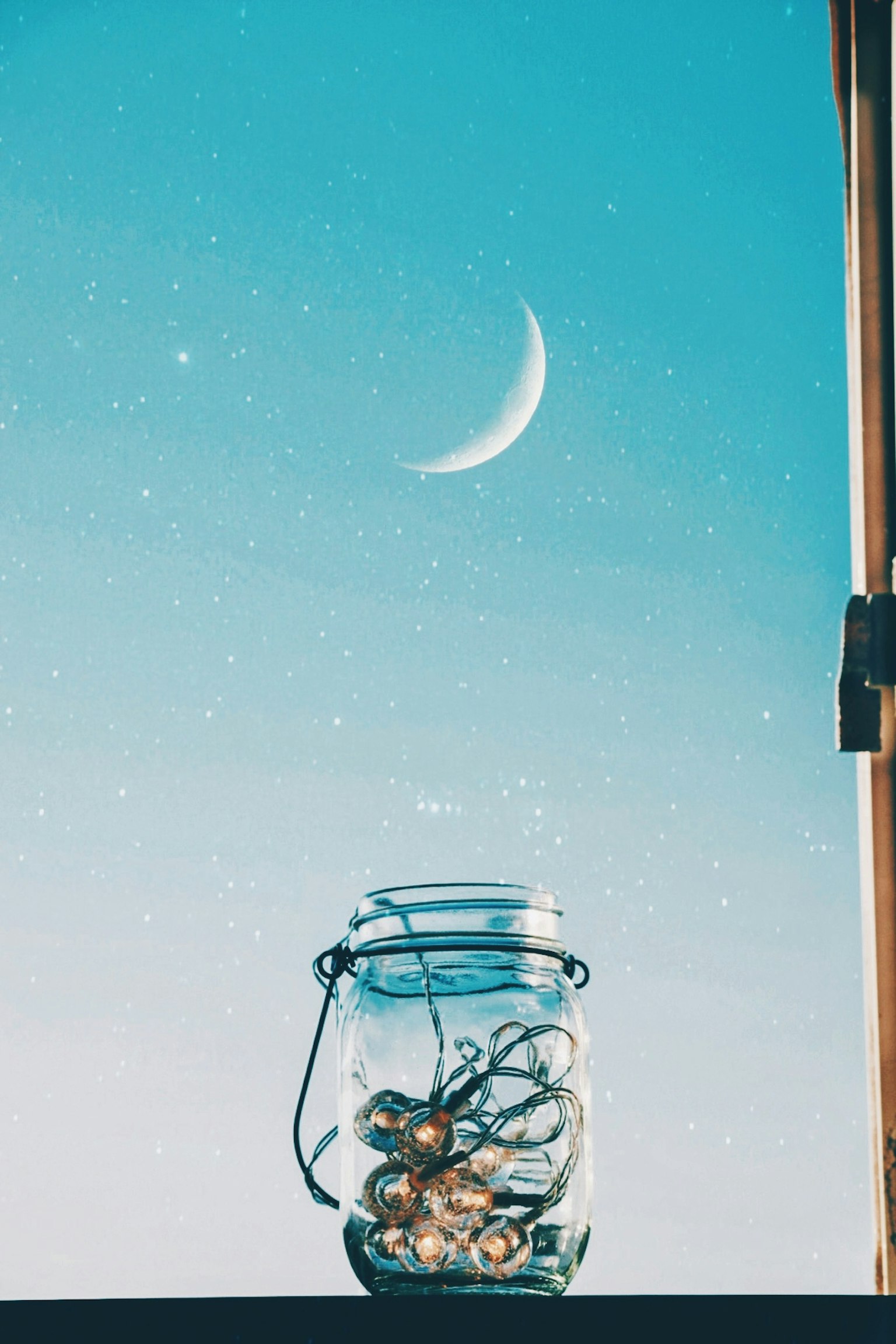 Sebuah toples kaca penuh dengan barang dekoratif di latar belakang bulan sabit di langit biru