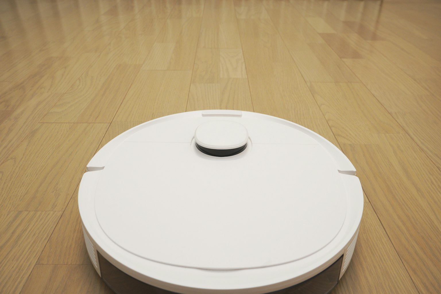 Un aspirateur robot blanc sur un sol en bois