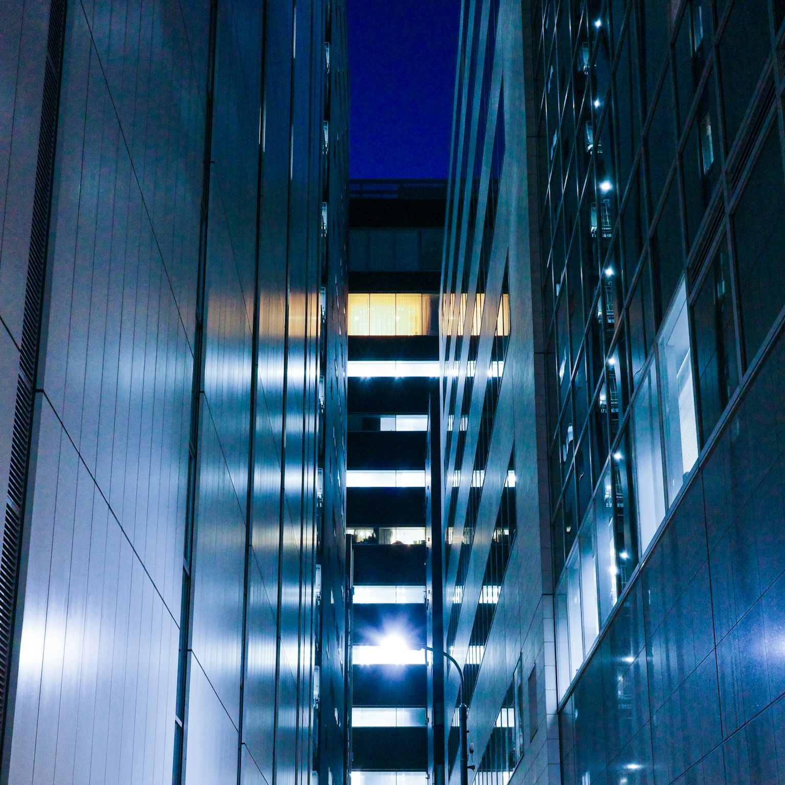 Allée étroite entre des bâtiments modernes illuminés la nuit
