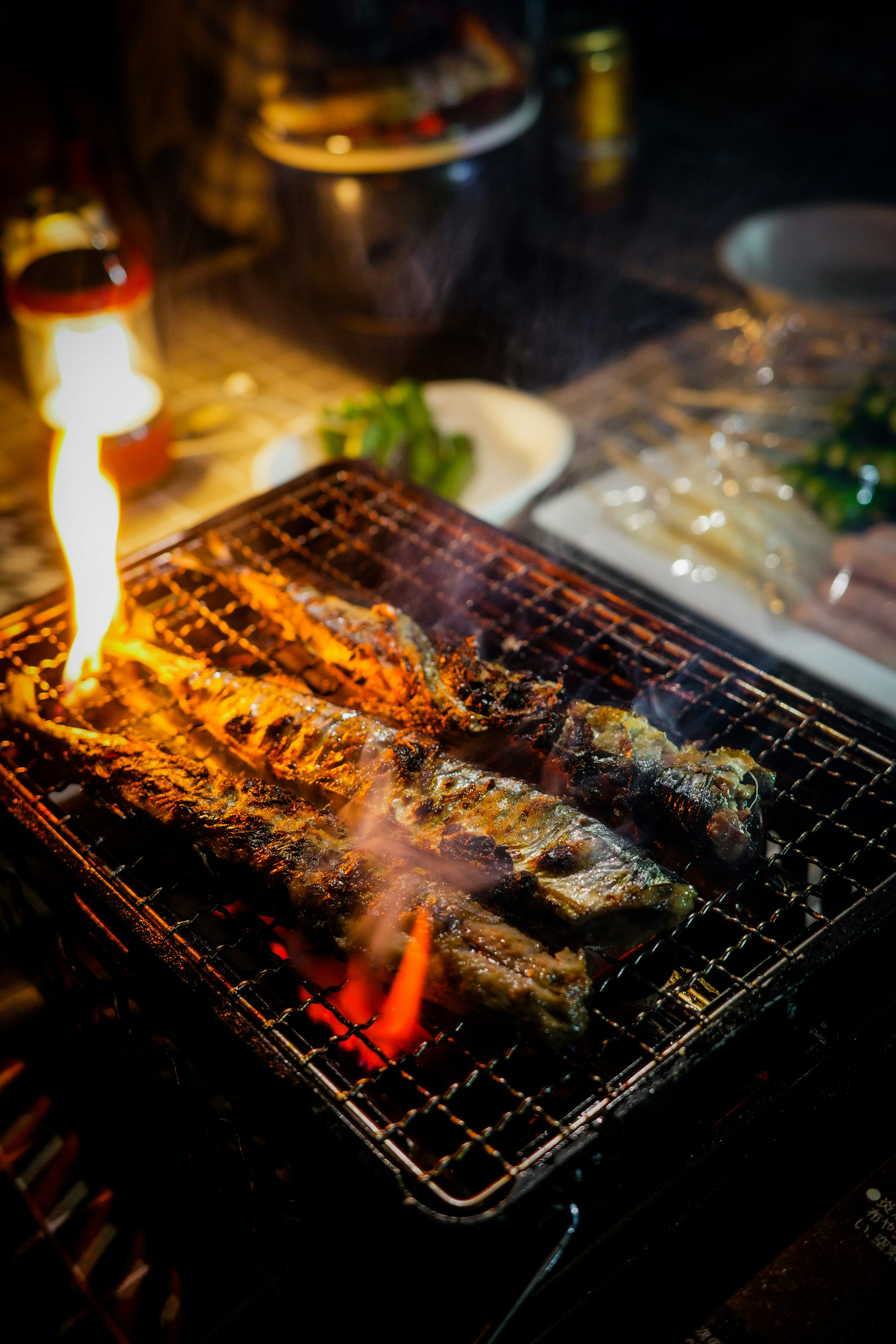 炭火で焼かれる串焼きとグリルの炎のあるバーベキュー風景