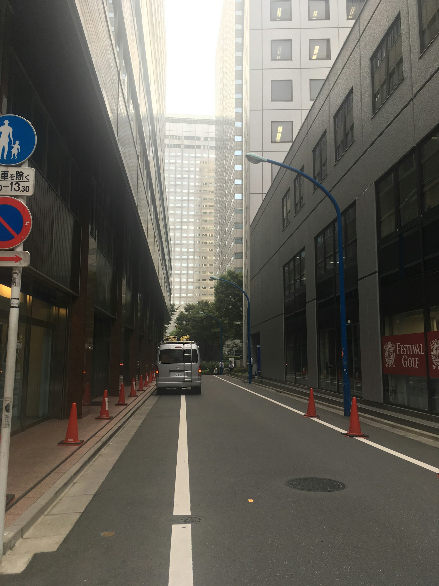Calle estrecha flanqueada por edificios con un carril blanco y conos rojos