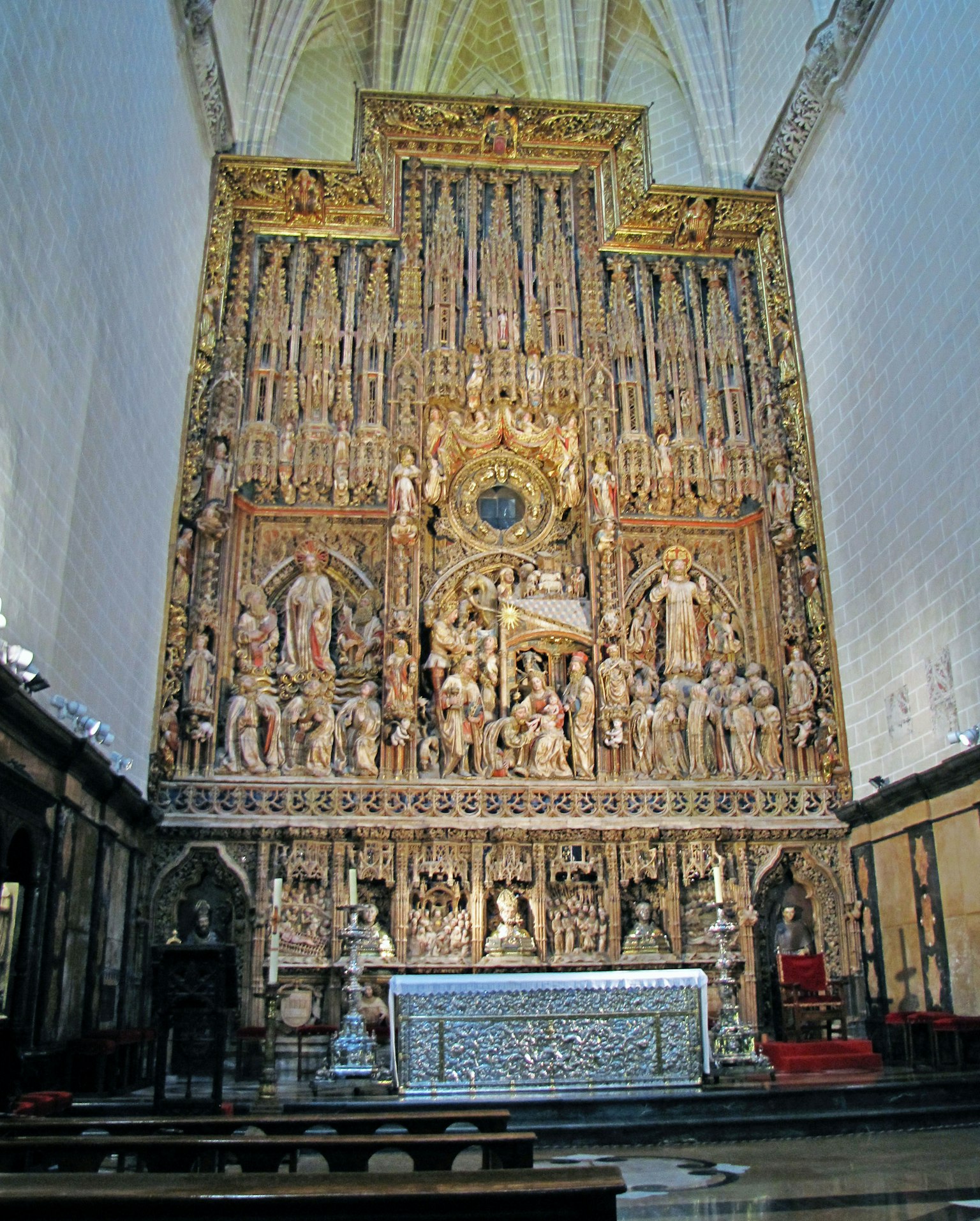 Altare di chiesa ornato con sculture intricate che raffigurano santi e angeli grande finestra circolare al centro