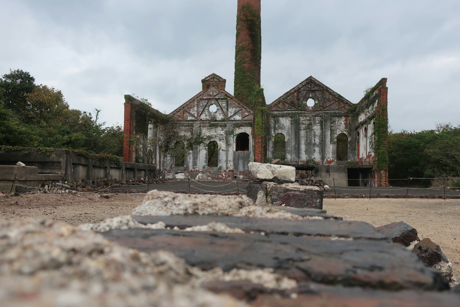 Ruined factory exterior with prominent chimney and moss-covered walls