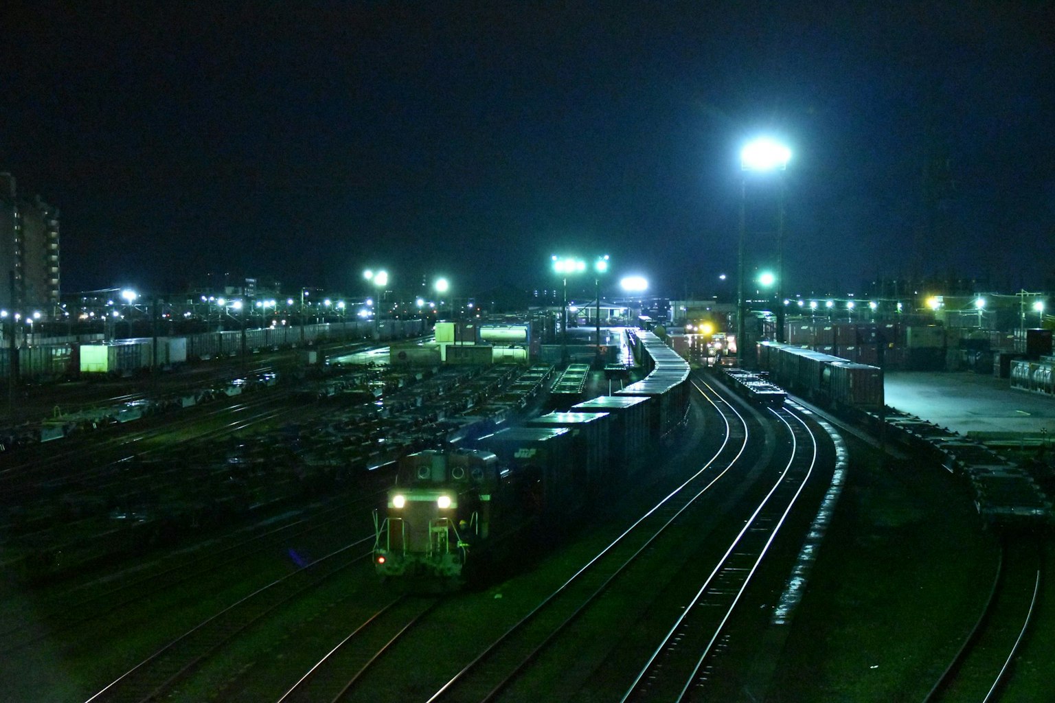 Scena ferroviaria notturna con treni e container