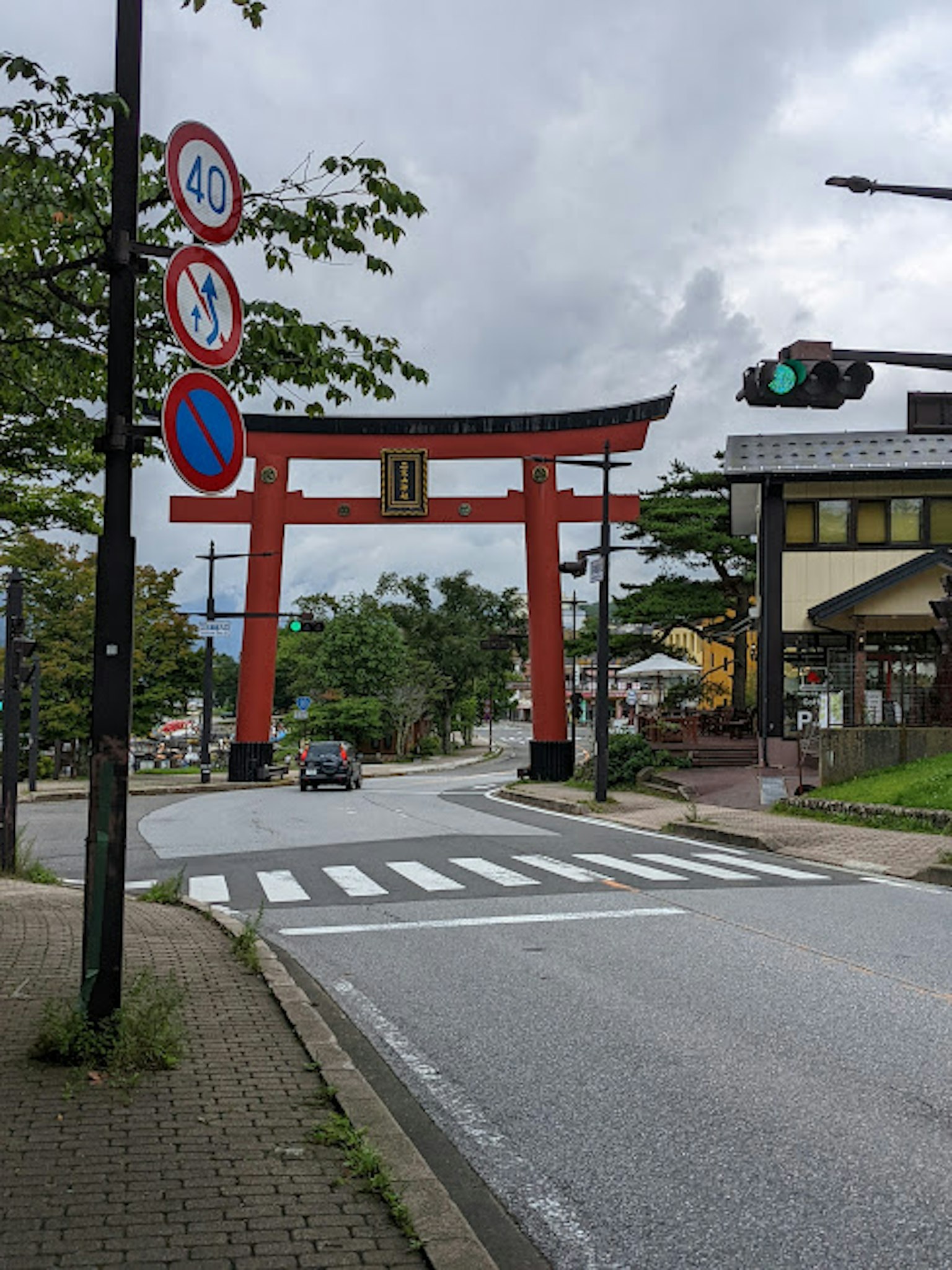 Red torii gate with traffic signs in a street setting