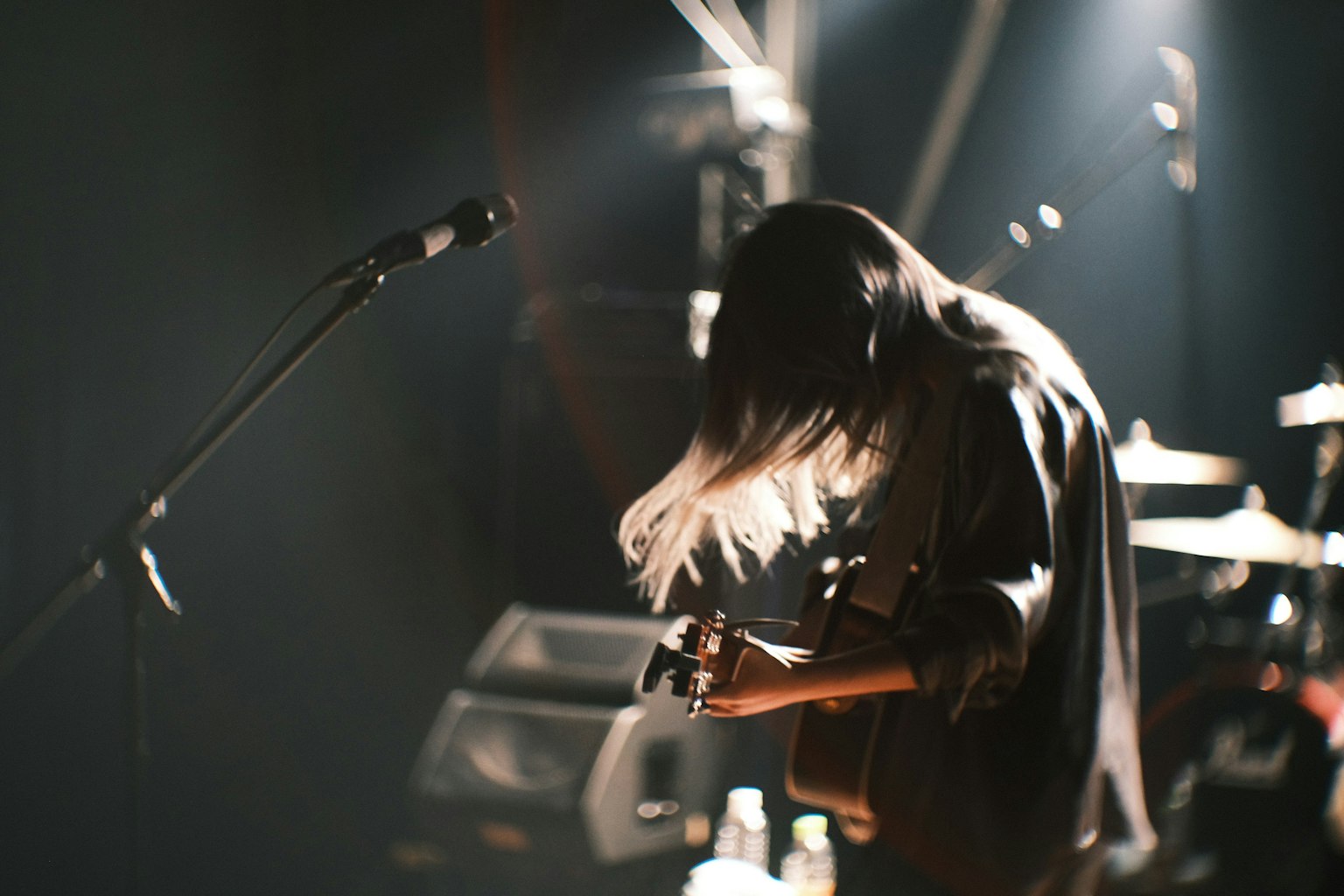 Guitarist performing live with flowing hair under spotlight