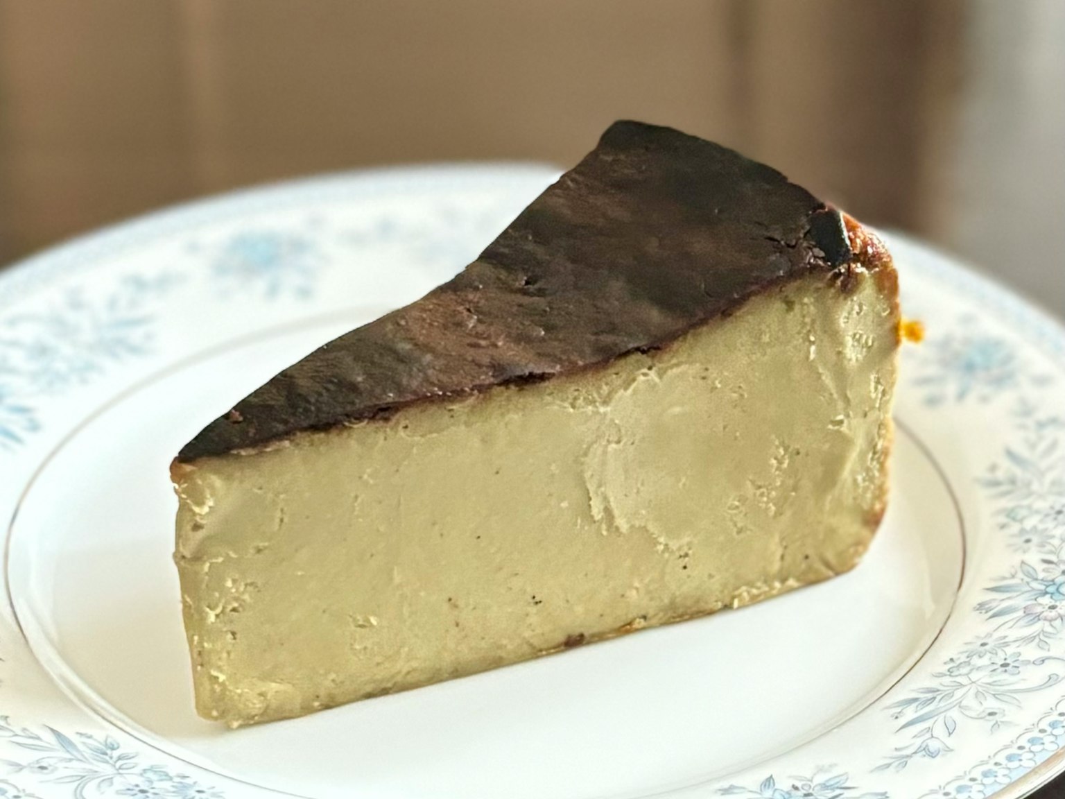 A slice of burnt cheesecake on a decorative white plate