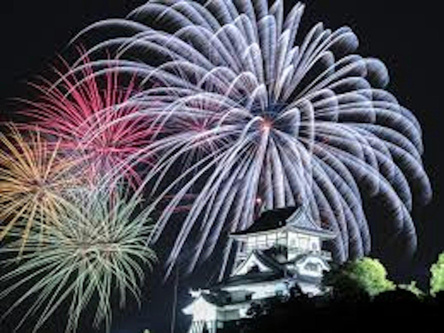 Fuochi d'artificio colorati che illuminano il cielo notturno sopra un castello tradizionale