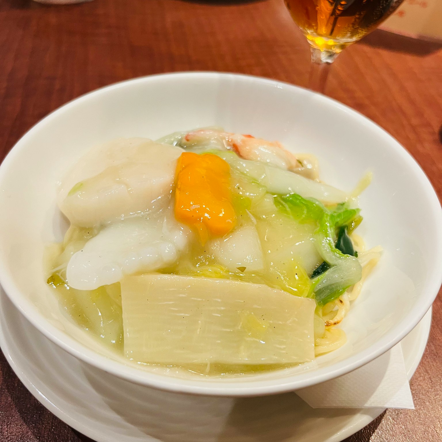 白色碗中盛著蔬菜和海鮮，特色是綠色蔬菜和橙色海膽