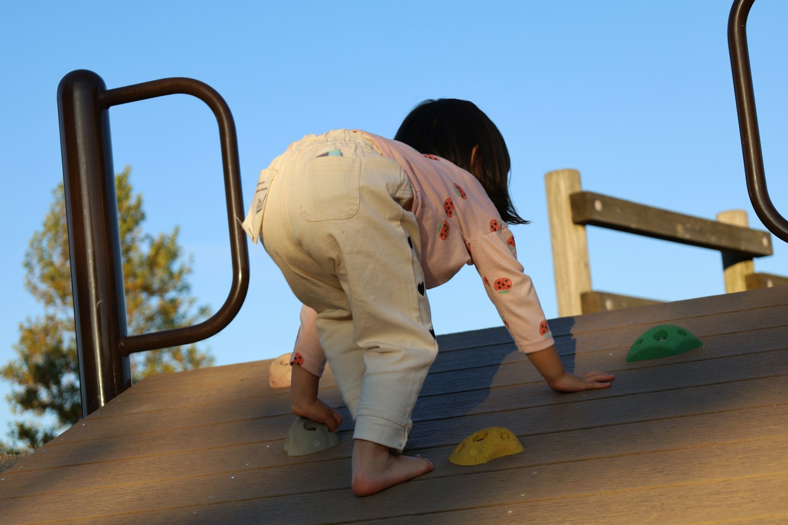 Kind, das an einer Kletterwand auf einem Spielplatz klettert