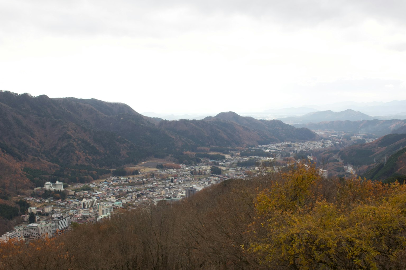Une ville entourée de montagnes sous un ciel nuageux