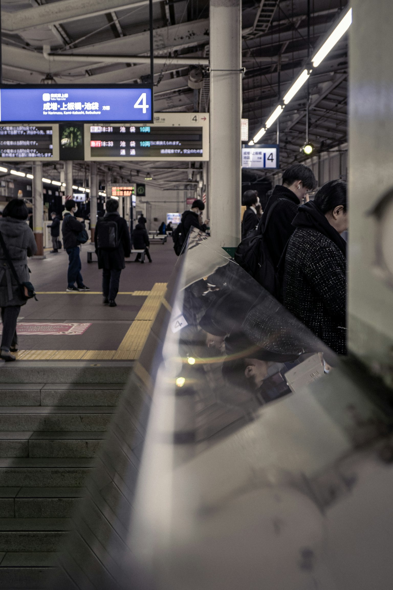 People waiting on a train platform with visible signage and a busy atmosphere