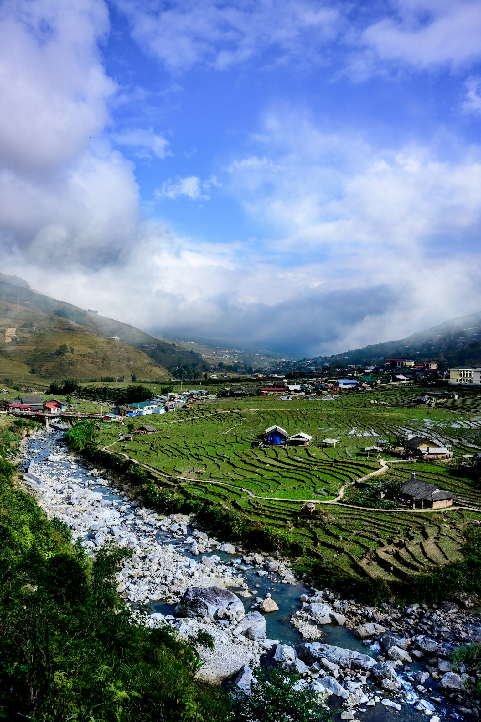 Scenic rural landscape with green fields and a river under a blue sky