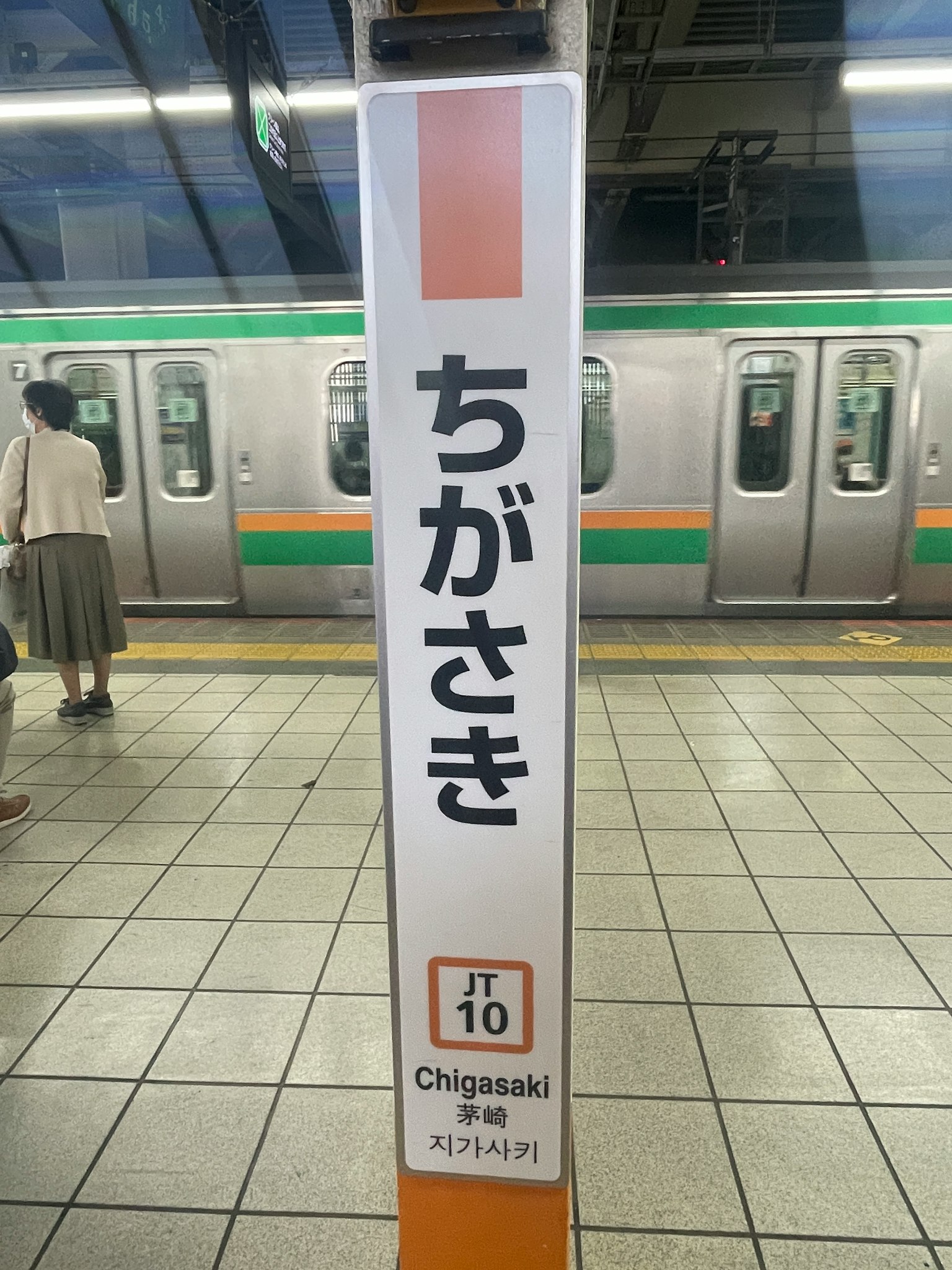 Cartel de la estación Chigasaki con tren en espera