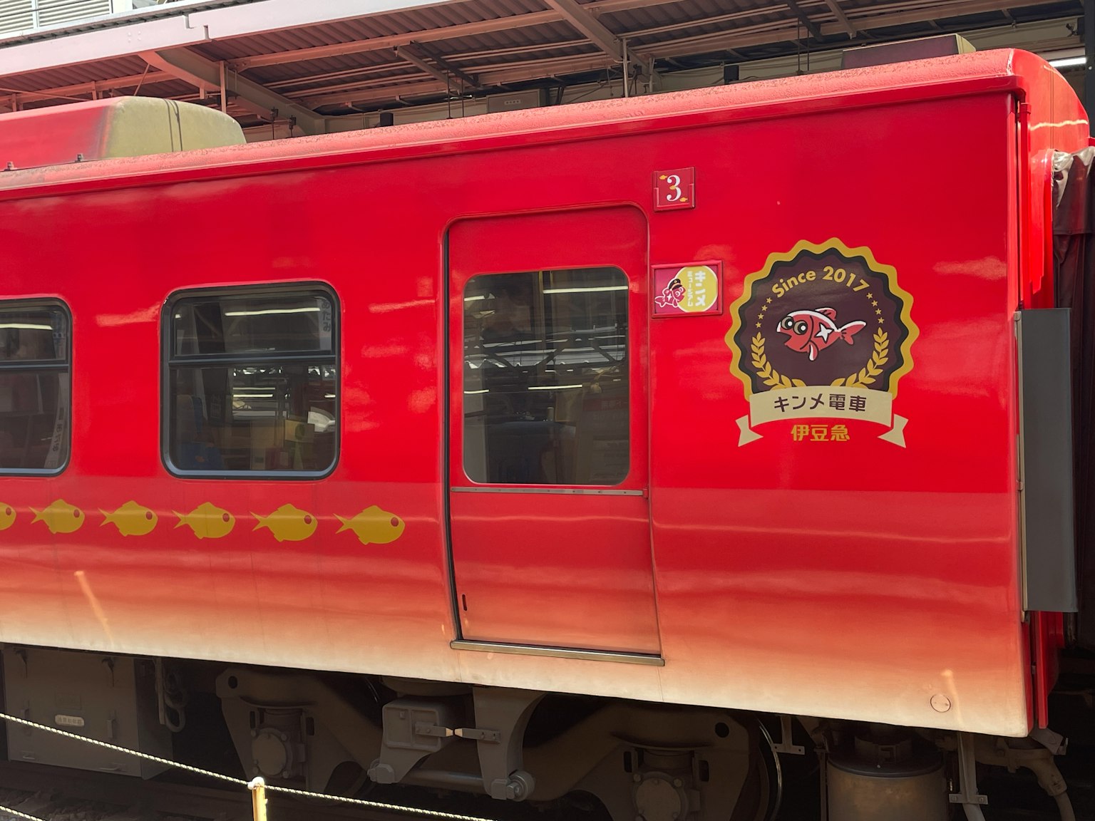 Side view of a red train featuring a logo and decorative elements