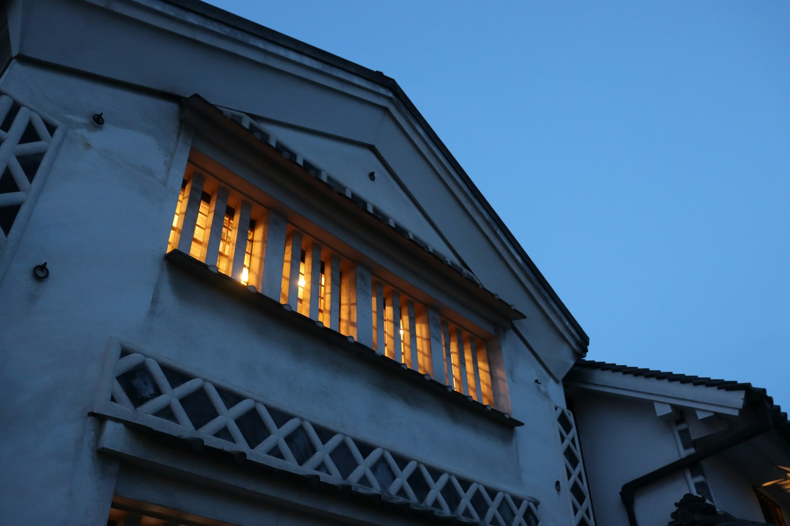 Ein Gebäude unter einem blauen Himmel mit warmem Licht, das durch die Fenster strahlt