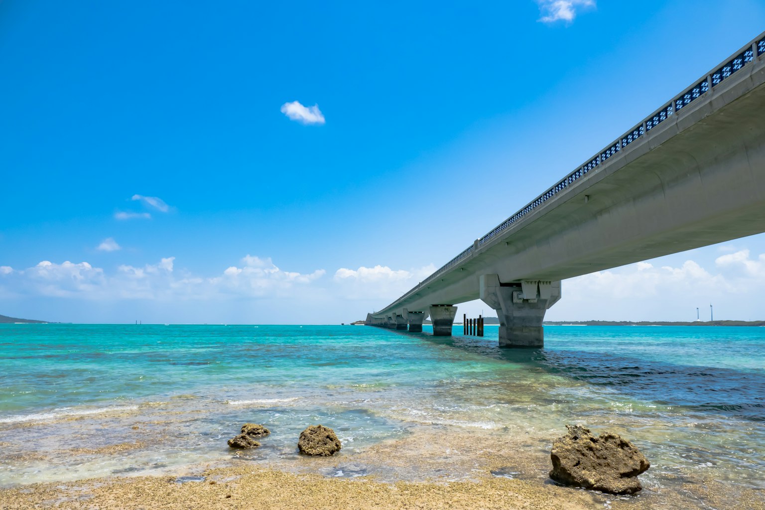 Una vista panoramica di un ponte sopra acqua turchese con rocce visibili sotto