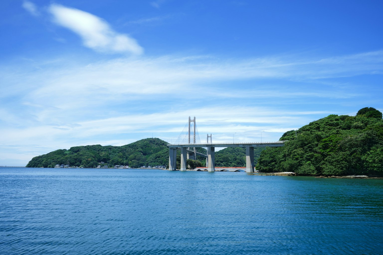 Puente sobre agua azul tranquila con islas verdes al fondo