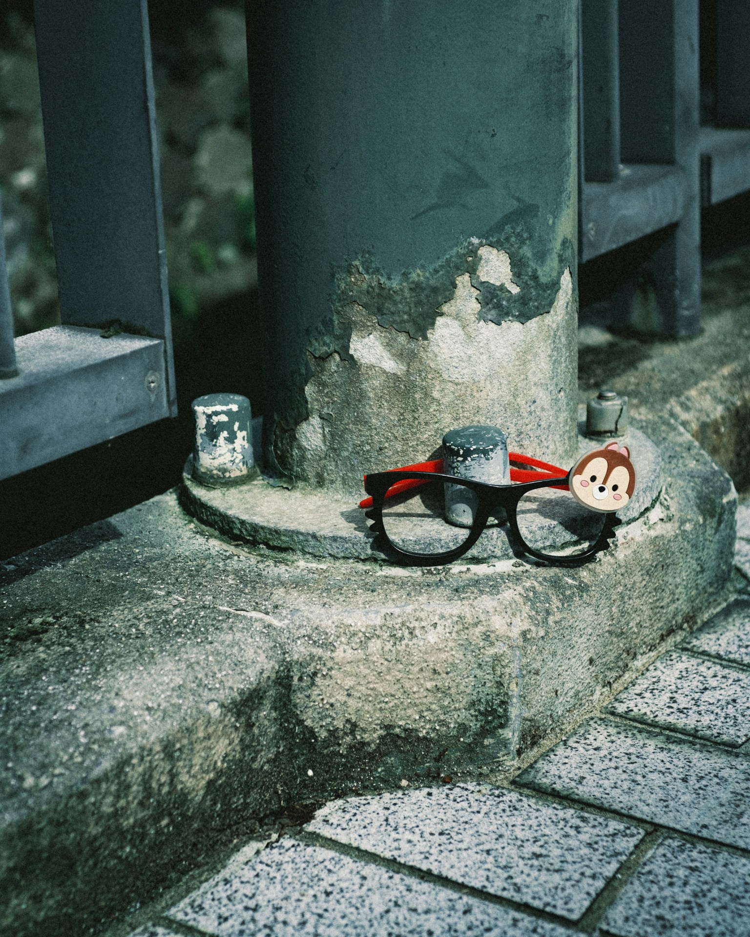 Brille mit rotem Band und einem kleinen Charakter an der Ecke einer Betonstruktur platziert