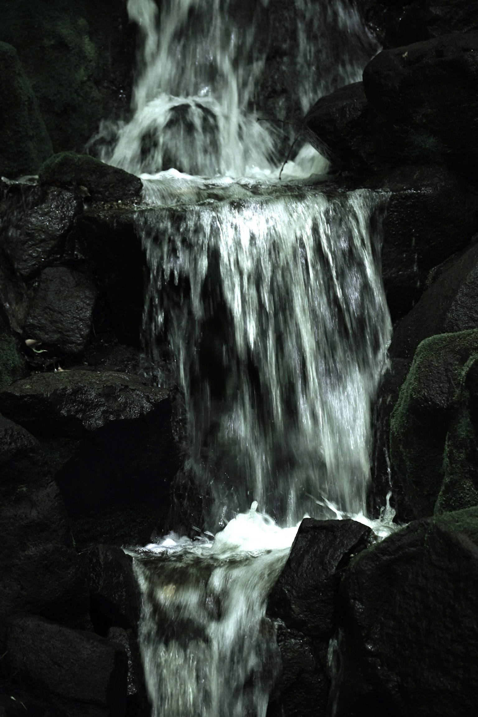 Air mengalir di antara batu gelap dalam air terjun