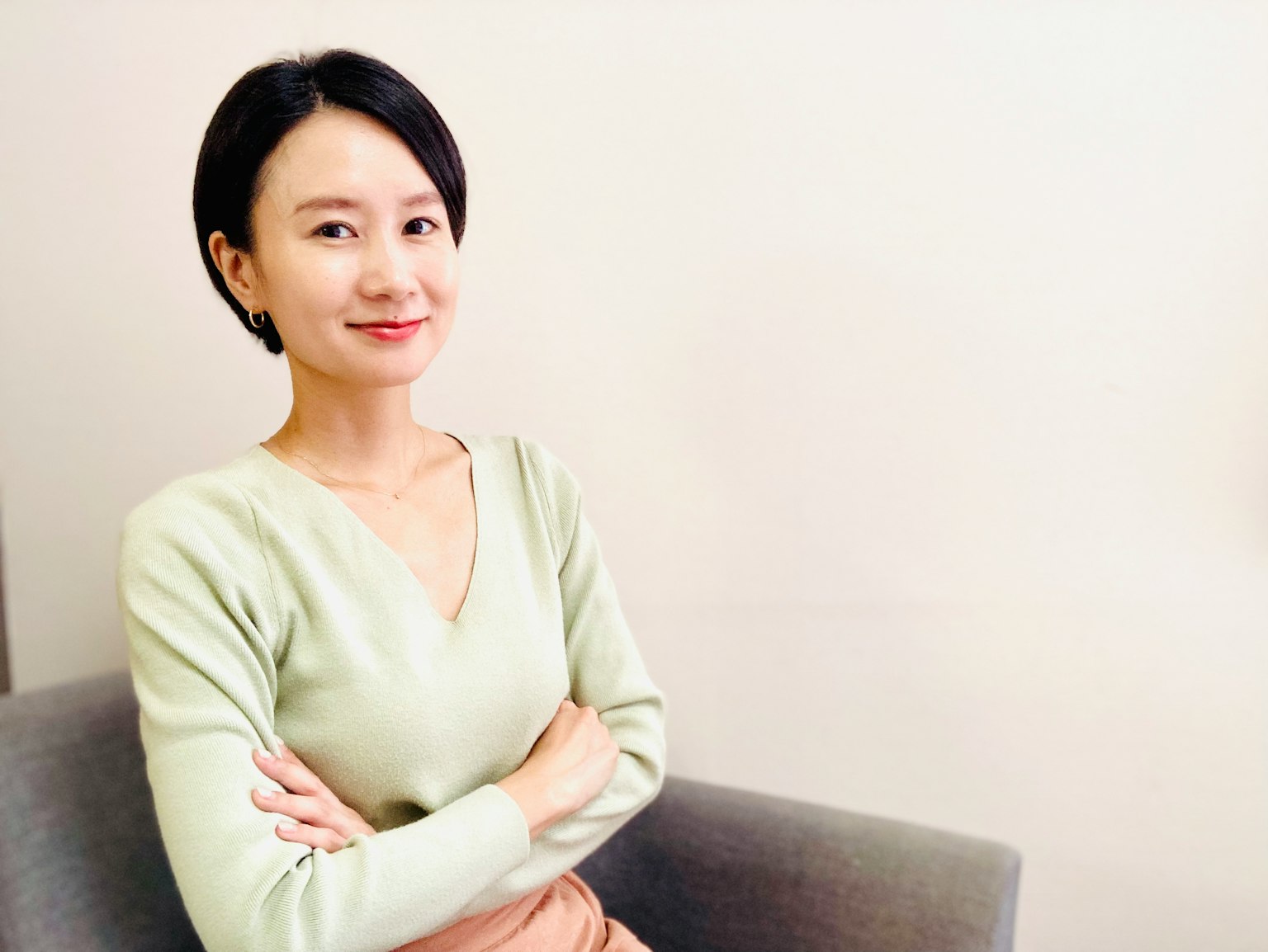 一位女性坐著雙臂交叉穿著柔和色彩的毛衣