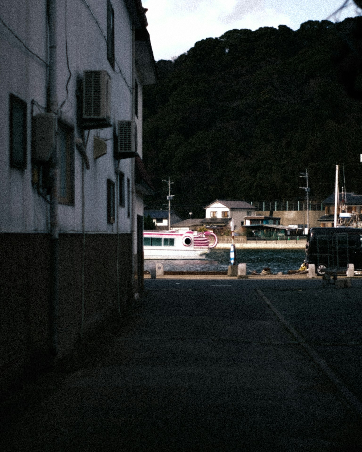 Narrow street with buildings and visible boats in the background