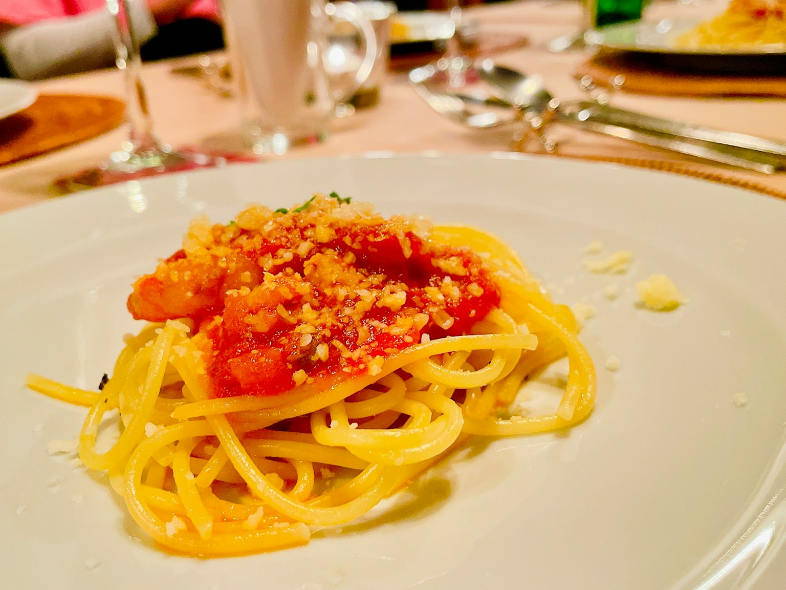 Plate of spaghetti topped with tomato sauce and breadcrumbs