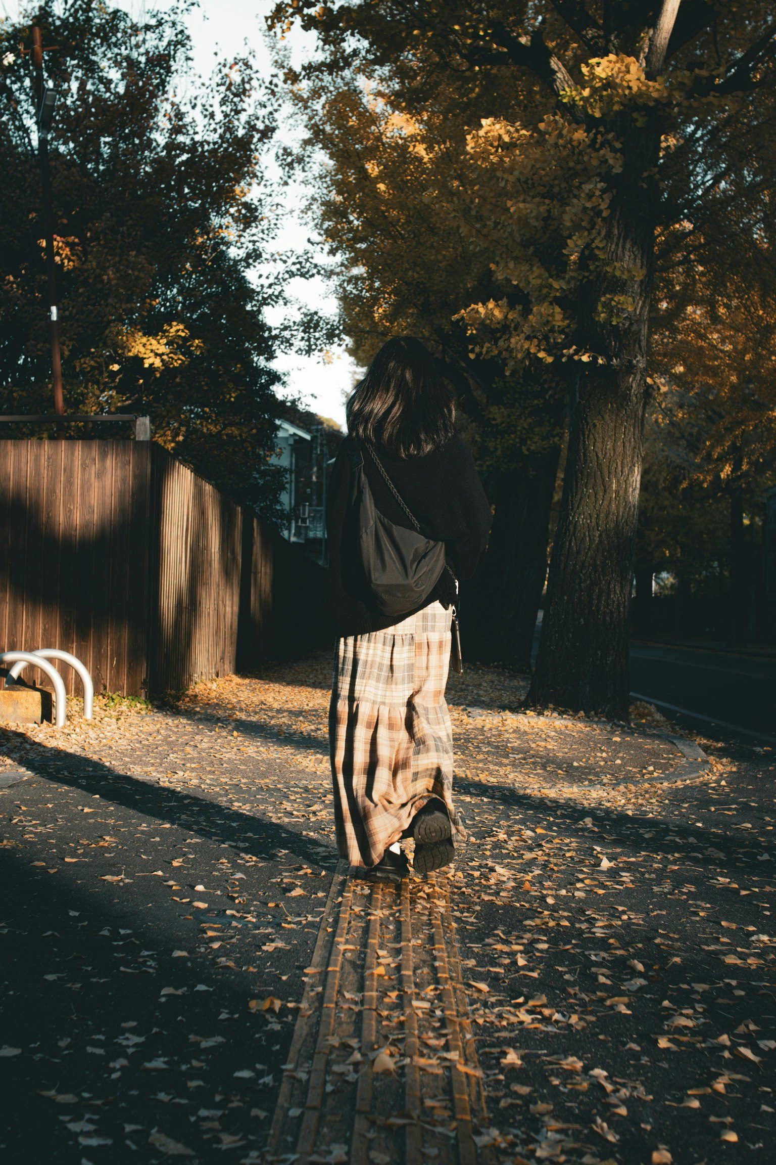 秋天公園裡走路的女人，地上有落葉