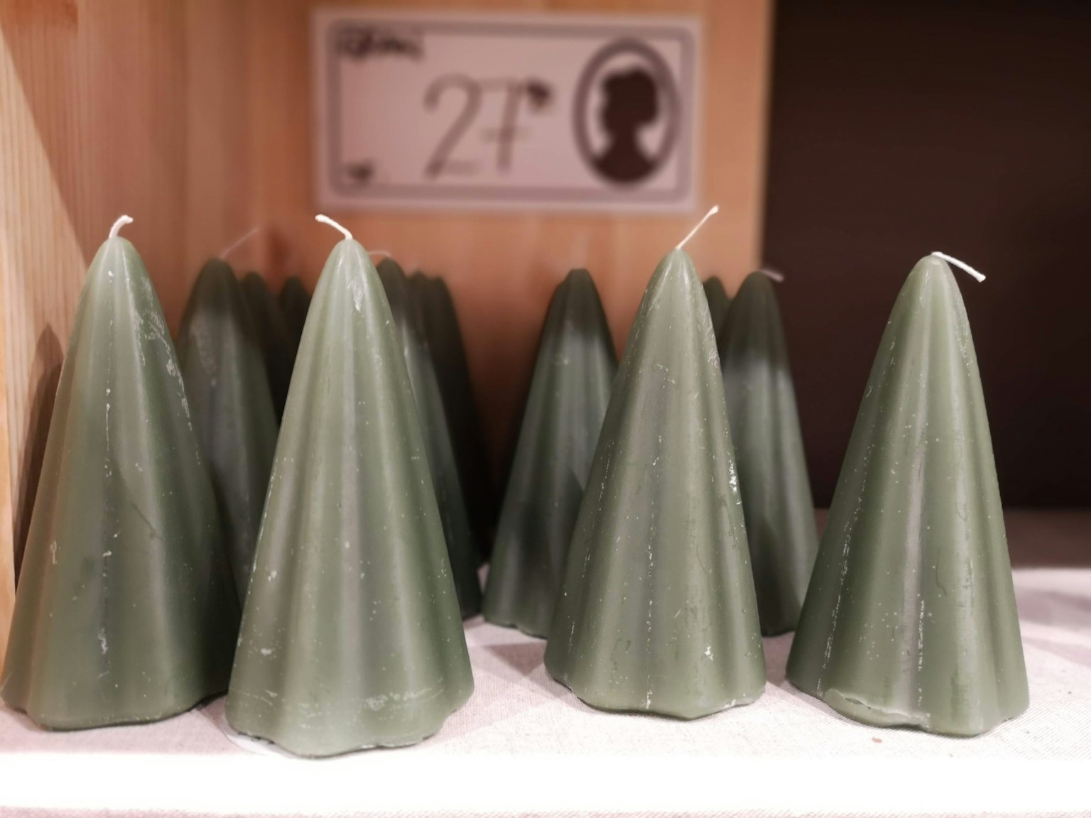 Image of green conical candles arranged on a shelf with a silhouette price tag in the background