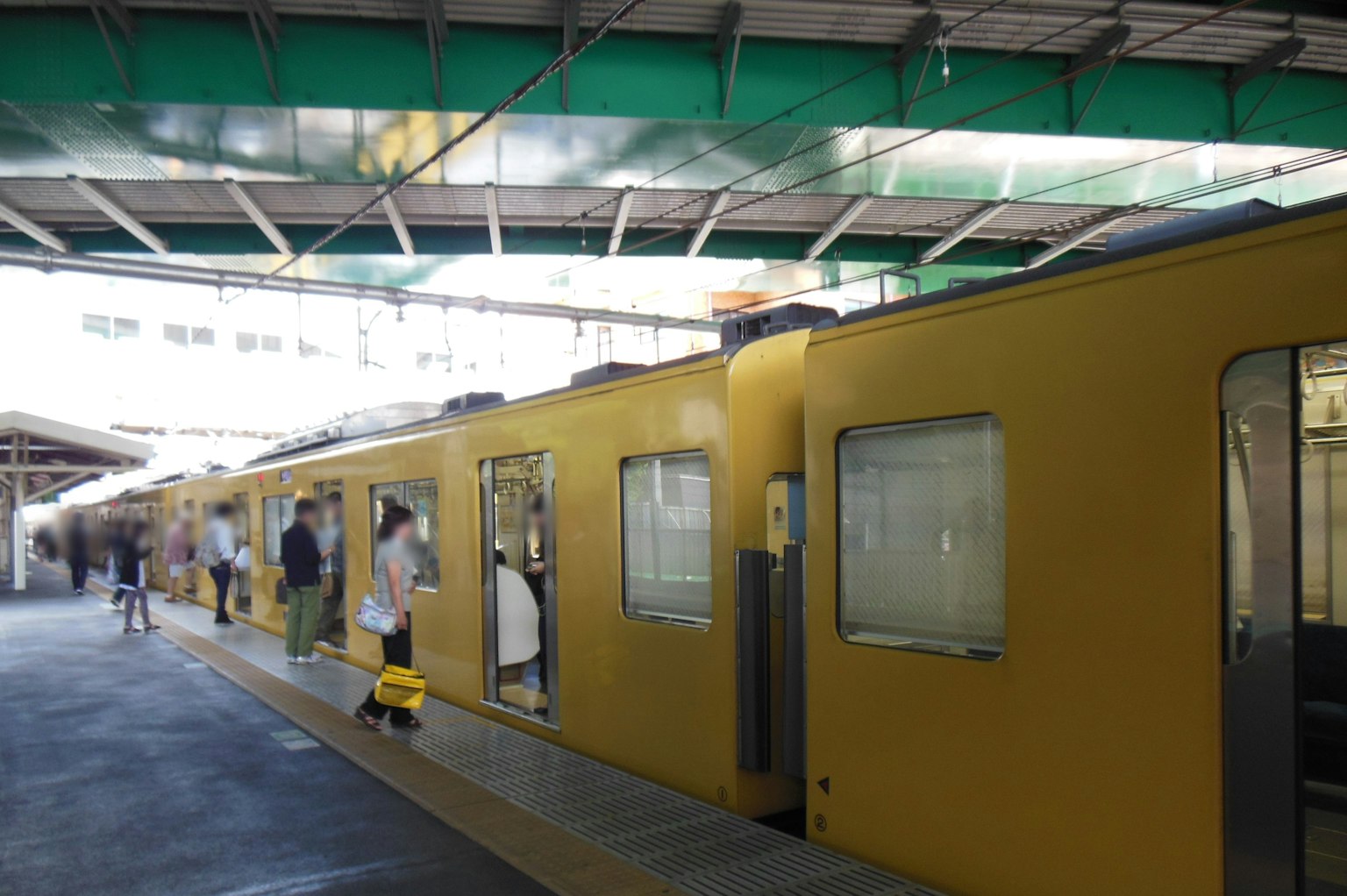 Tren amarillo en la estación con pasajeros subiendo y bajando