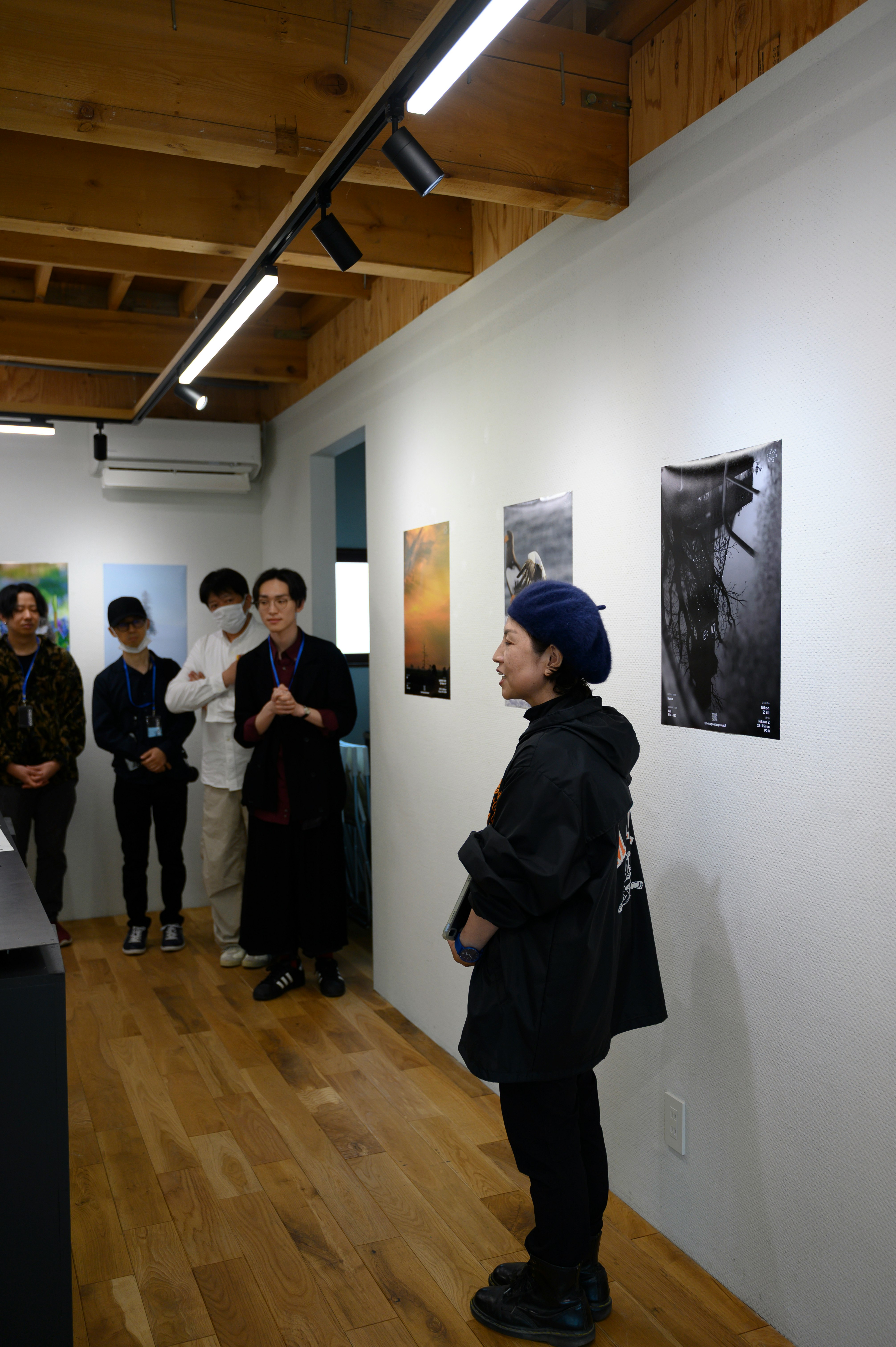 展示室の壁に並ぶアートポスターと来場者の横顔