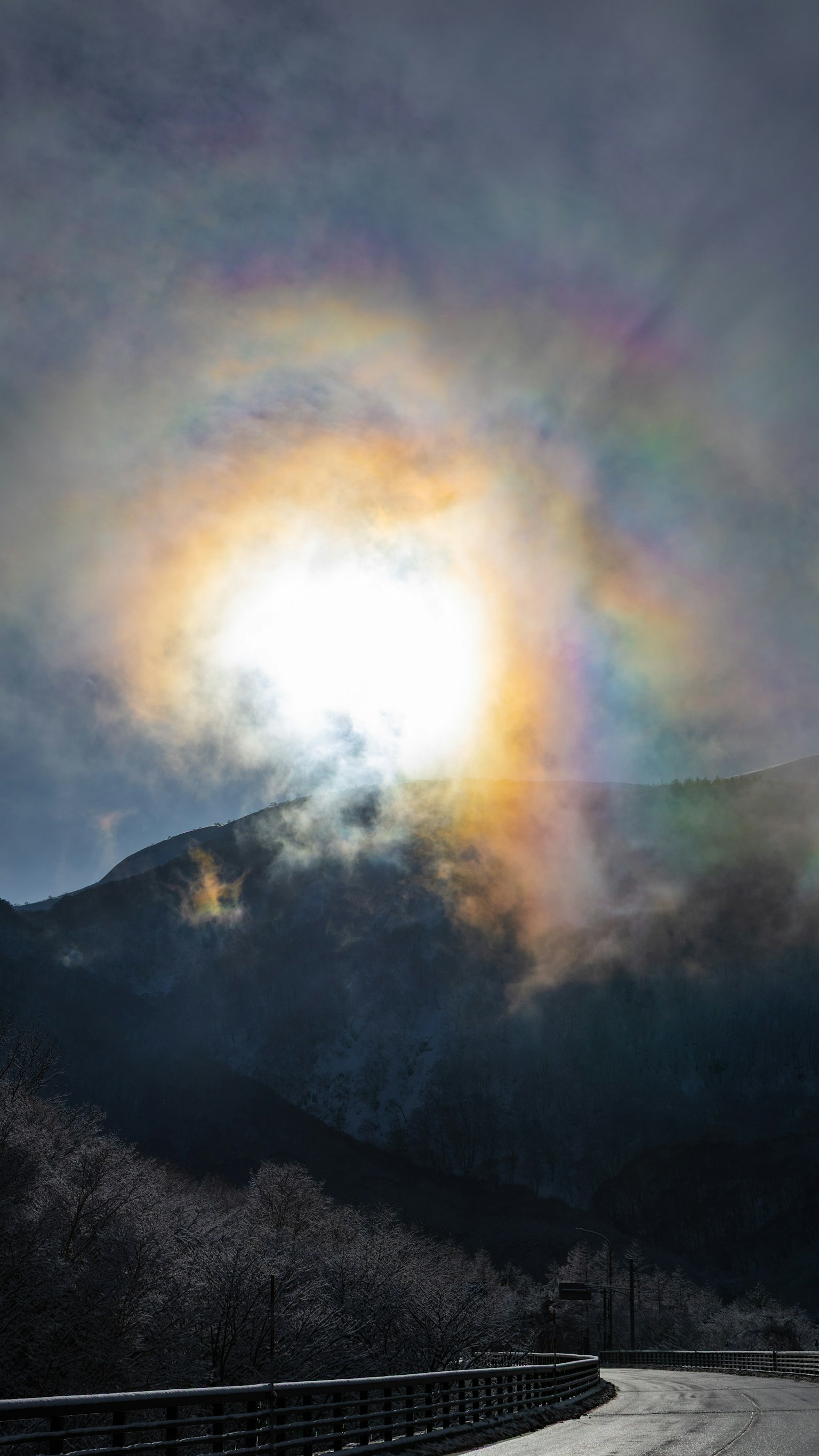 山の上に輝く太陽と虹色の光の環
