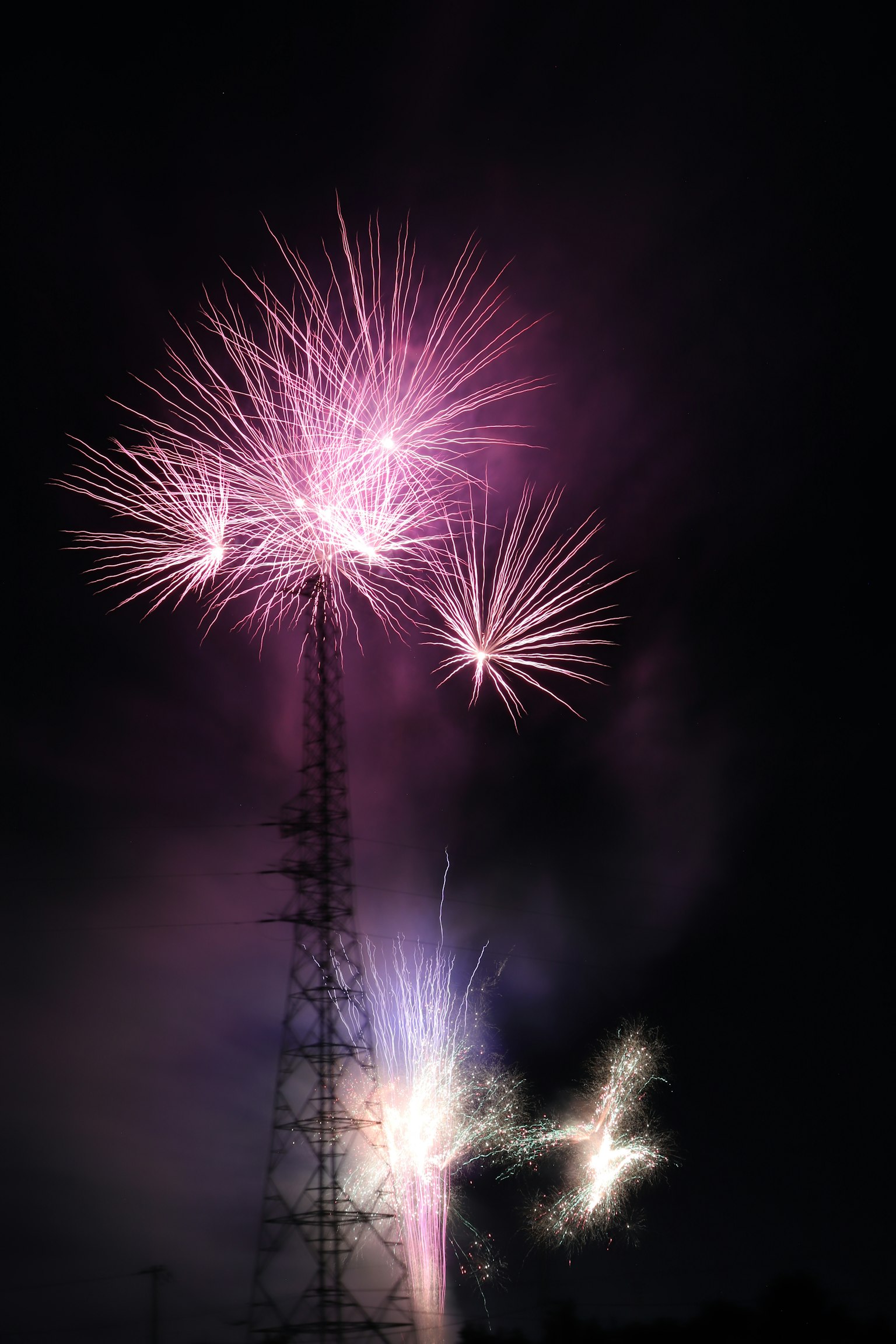 夜空中在传输塔附近绽放的烟花
