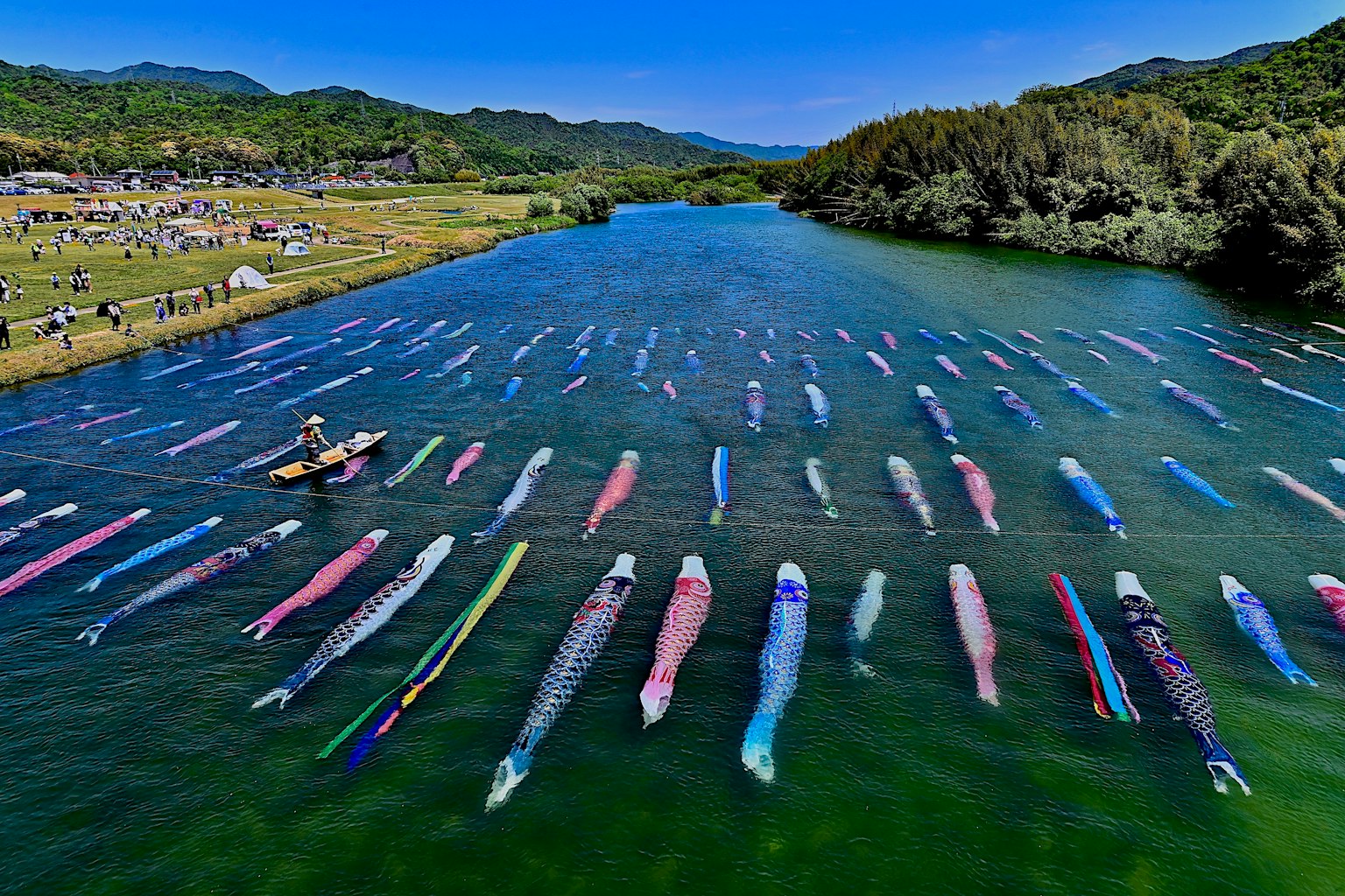 Équipements de pêche traditionnels colorés flottant dans une rivière bleue avec une personne travaillant dans un petit bateau