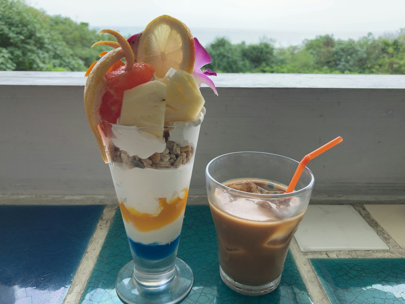 Ein bunter Parfait mit verschiedenen Früchten und ein Glas Eiskaffee