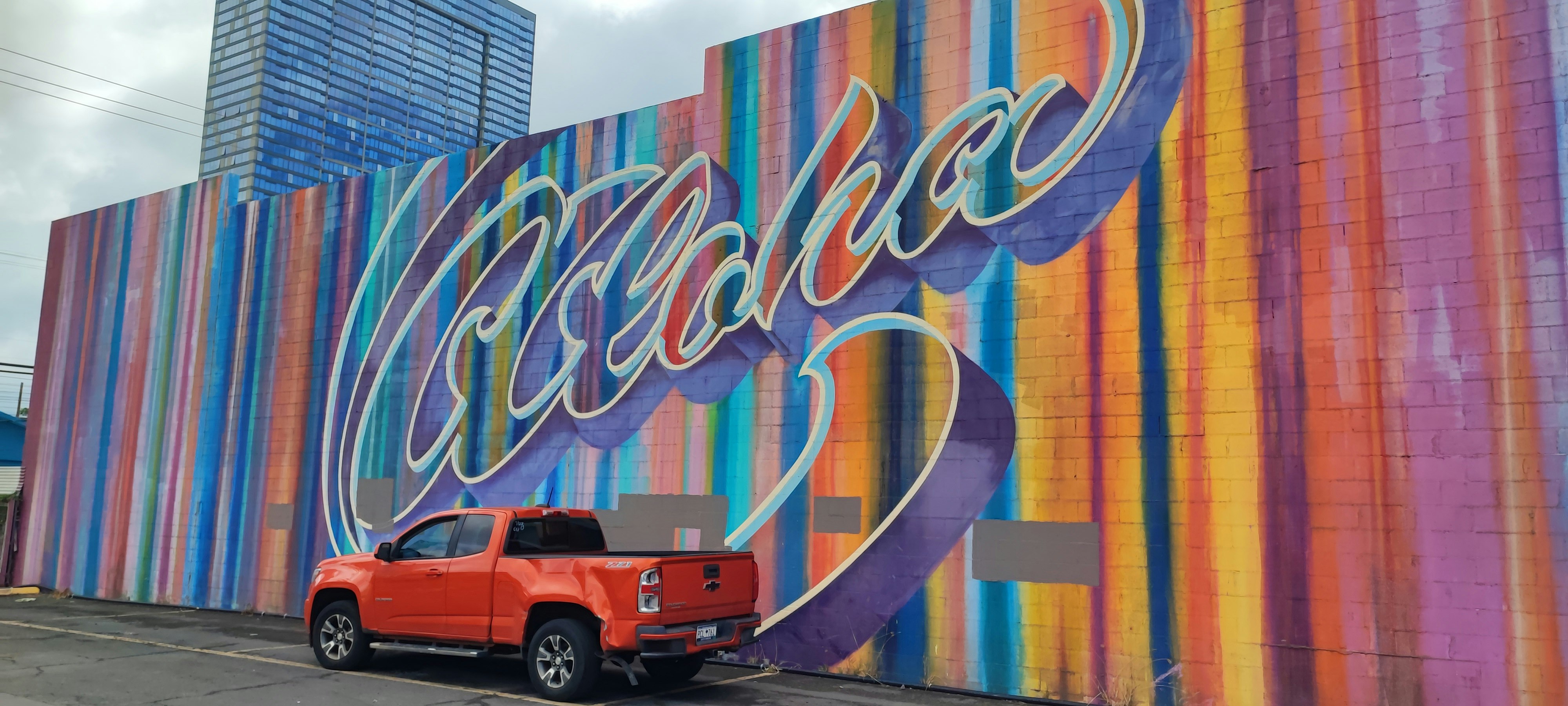 Una camioneta roja estacionada frente a un mural colorido