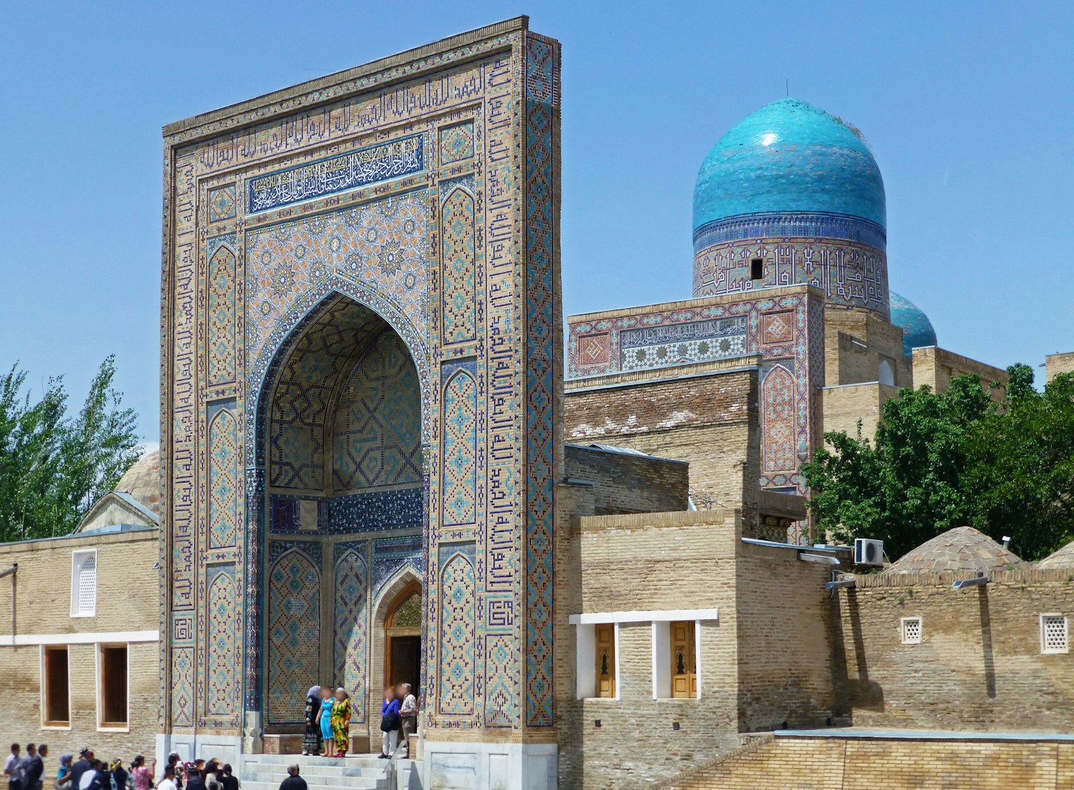 Historic building with a blue dome and arched entrance surrounded by visitors