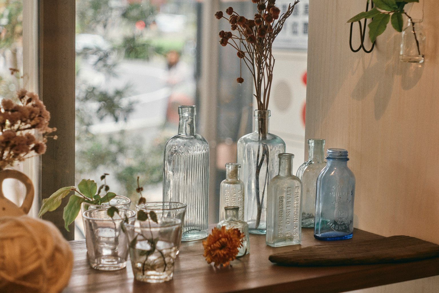 Una mesa de madera con varias botellas claras y plantas secas