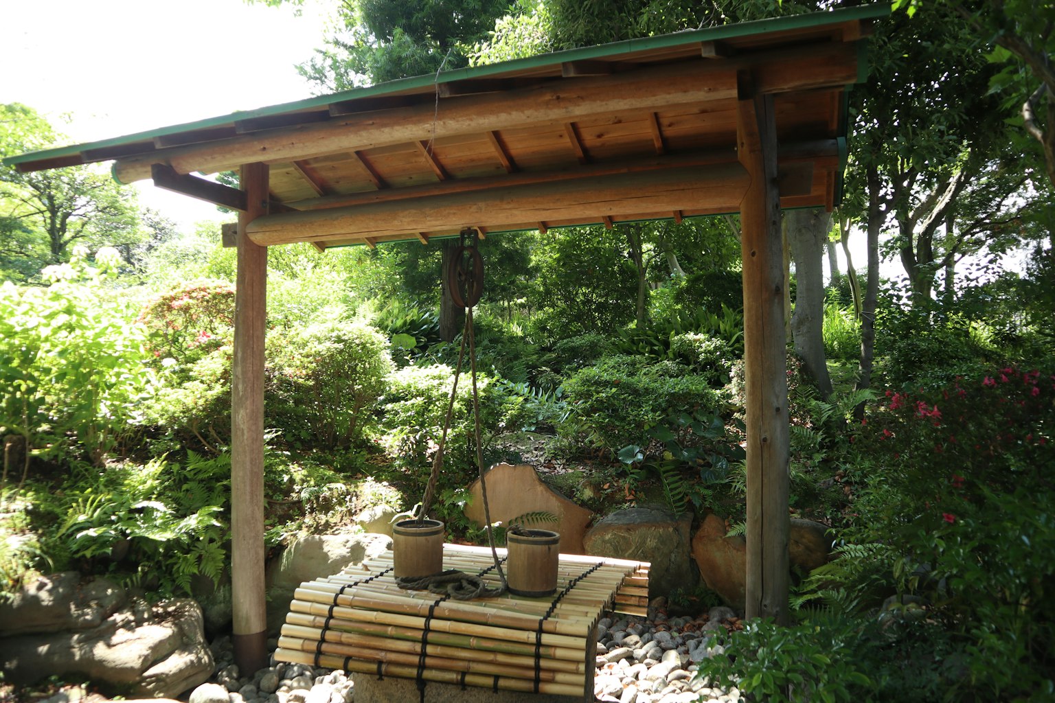 Caratteristica d'acqua tradizionale in un giardino giapponese con tetto in legno e secchi in bambù