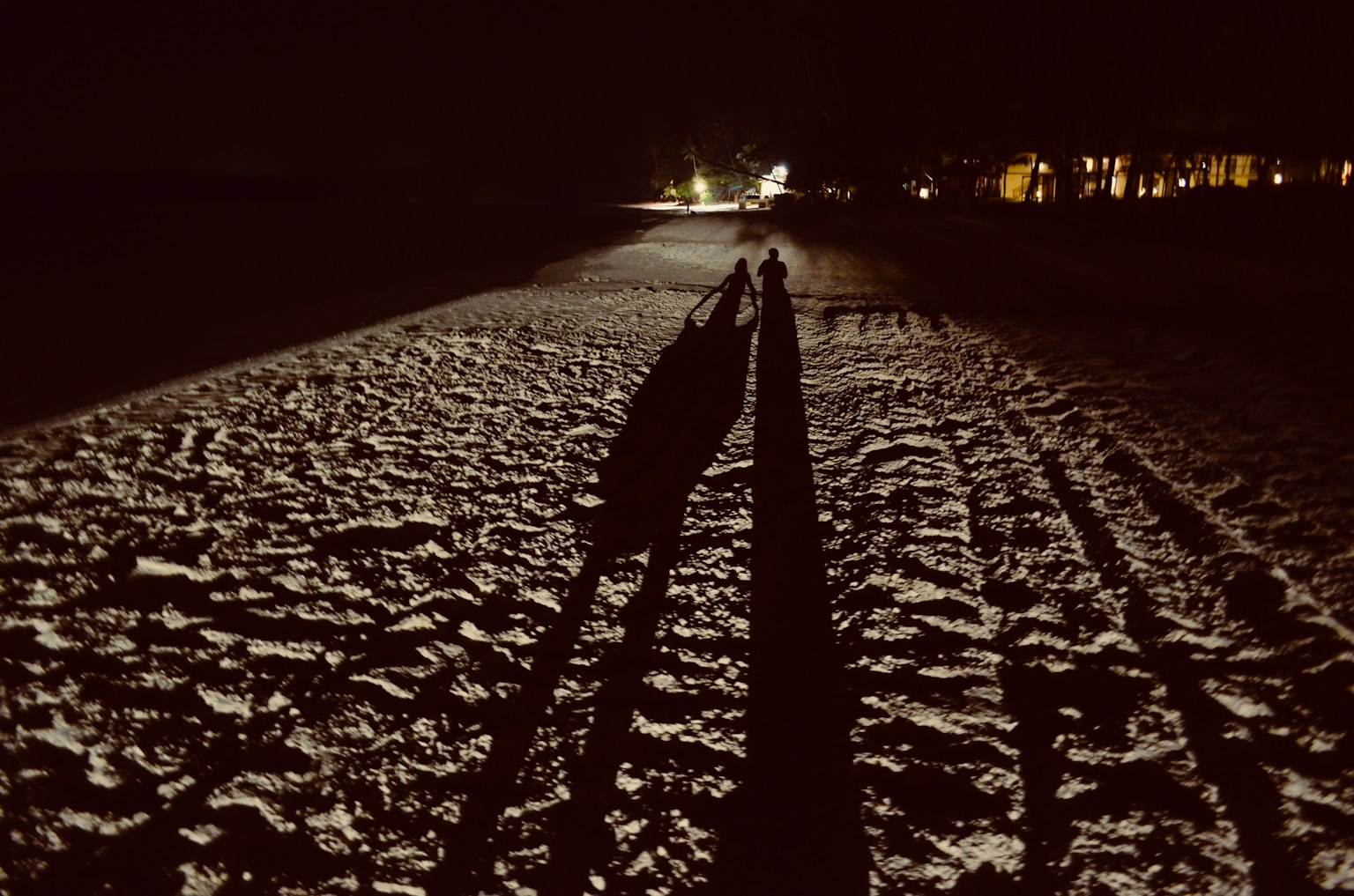 Des gens marchant sur la plage la nuit avec de longues ombres