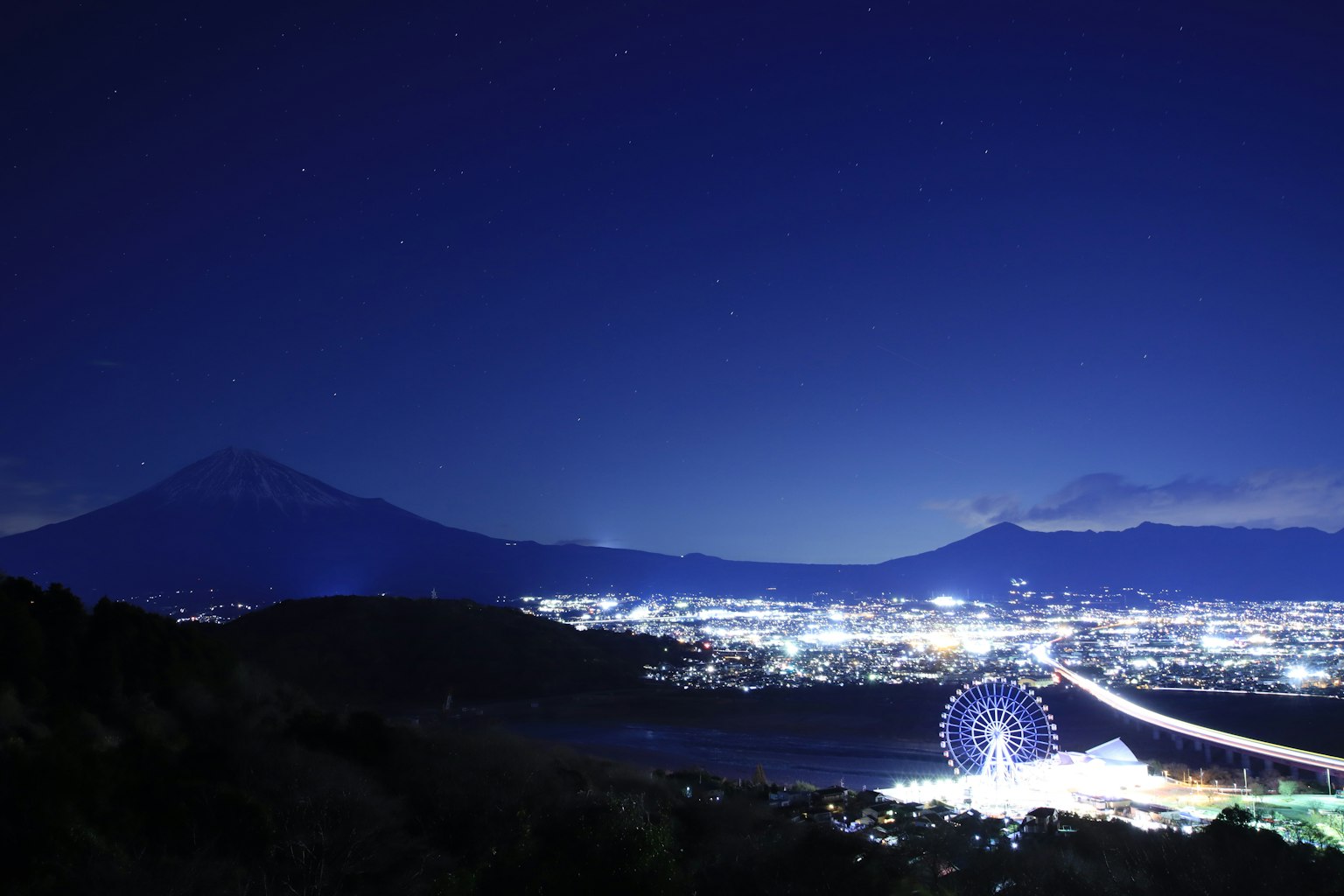 Nächtlicher Blick auf den Fuji und ein Riesenrad über der Stadt