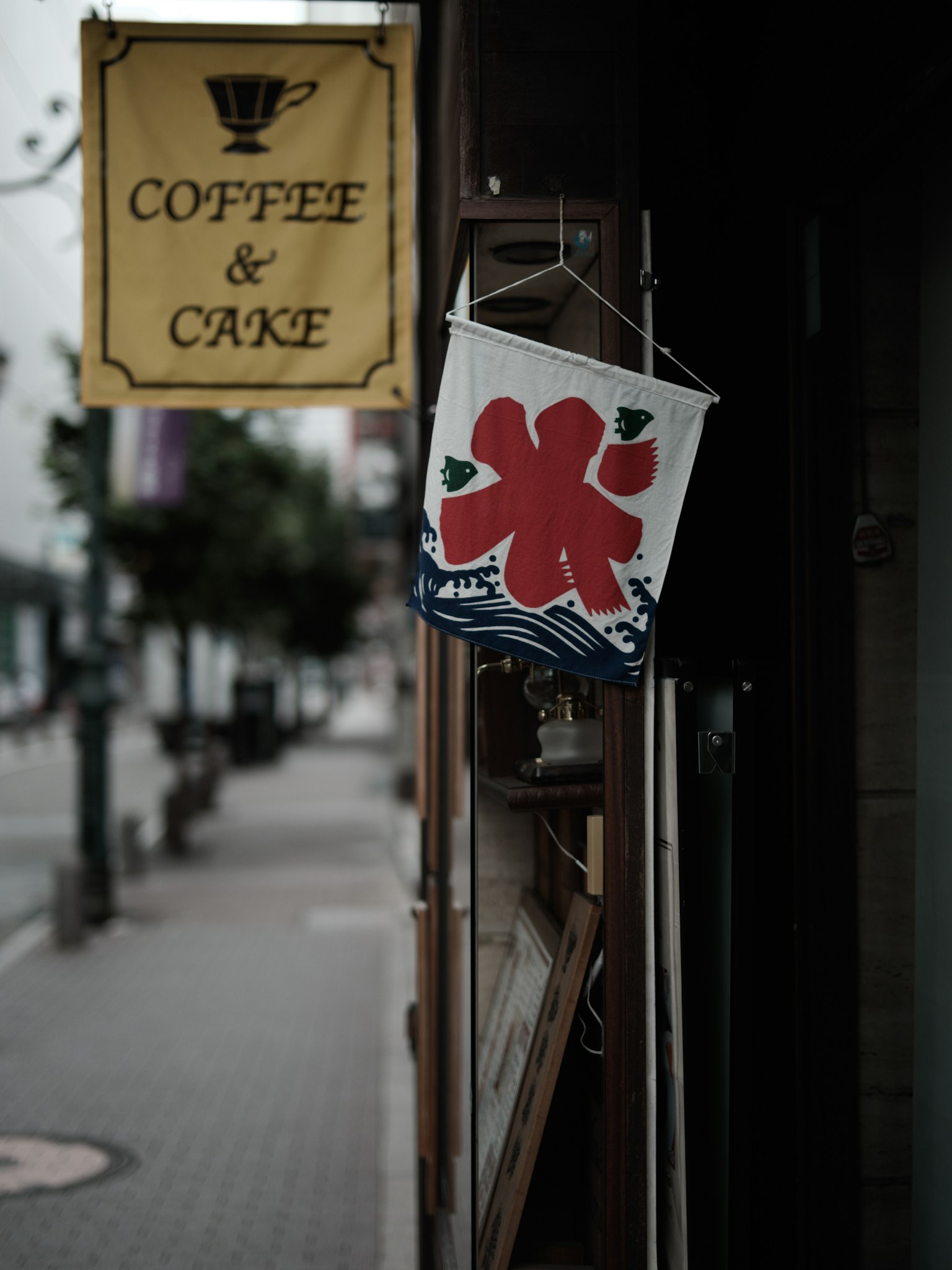 Extérieur de café avec une enseigne pour café et gâteau et un drapeau avec un motif floral rouge