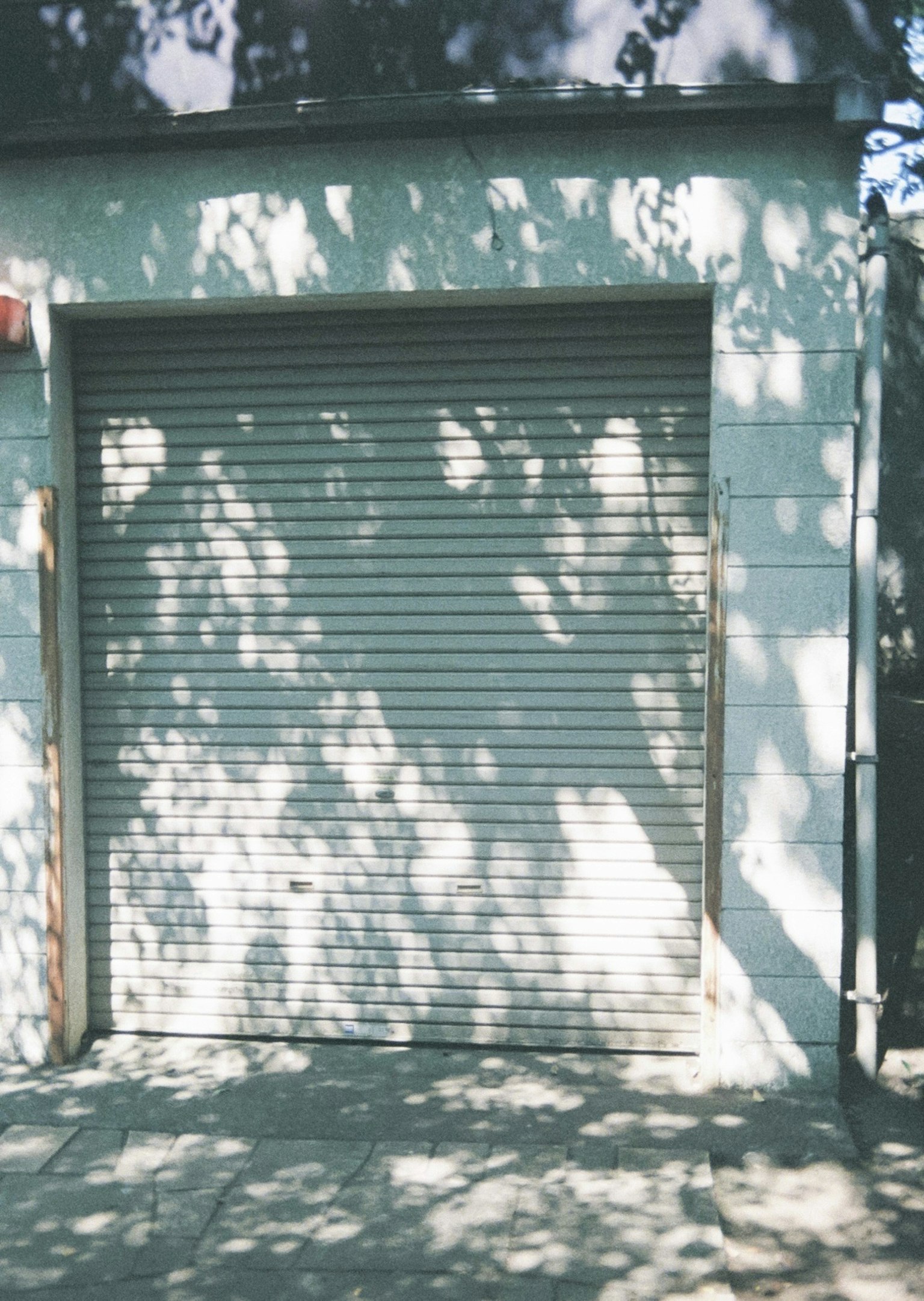 Vista esterna di un garage con una serranda e ombre proiettate