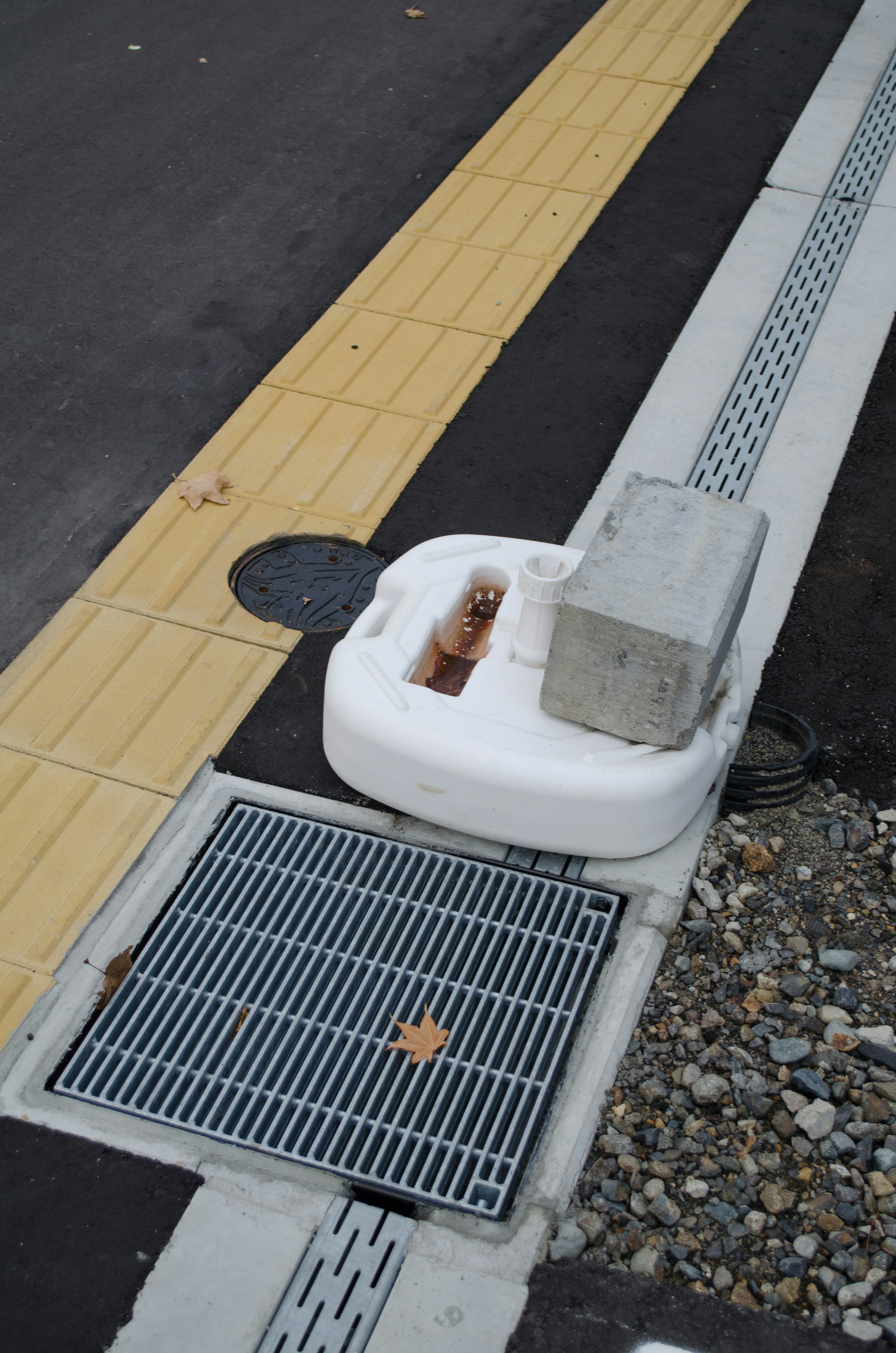 道路脇の排水溝と白いマンホール蓋