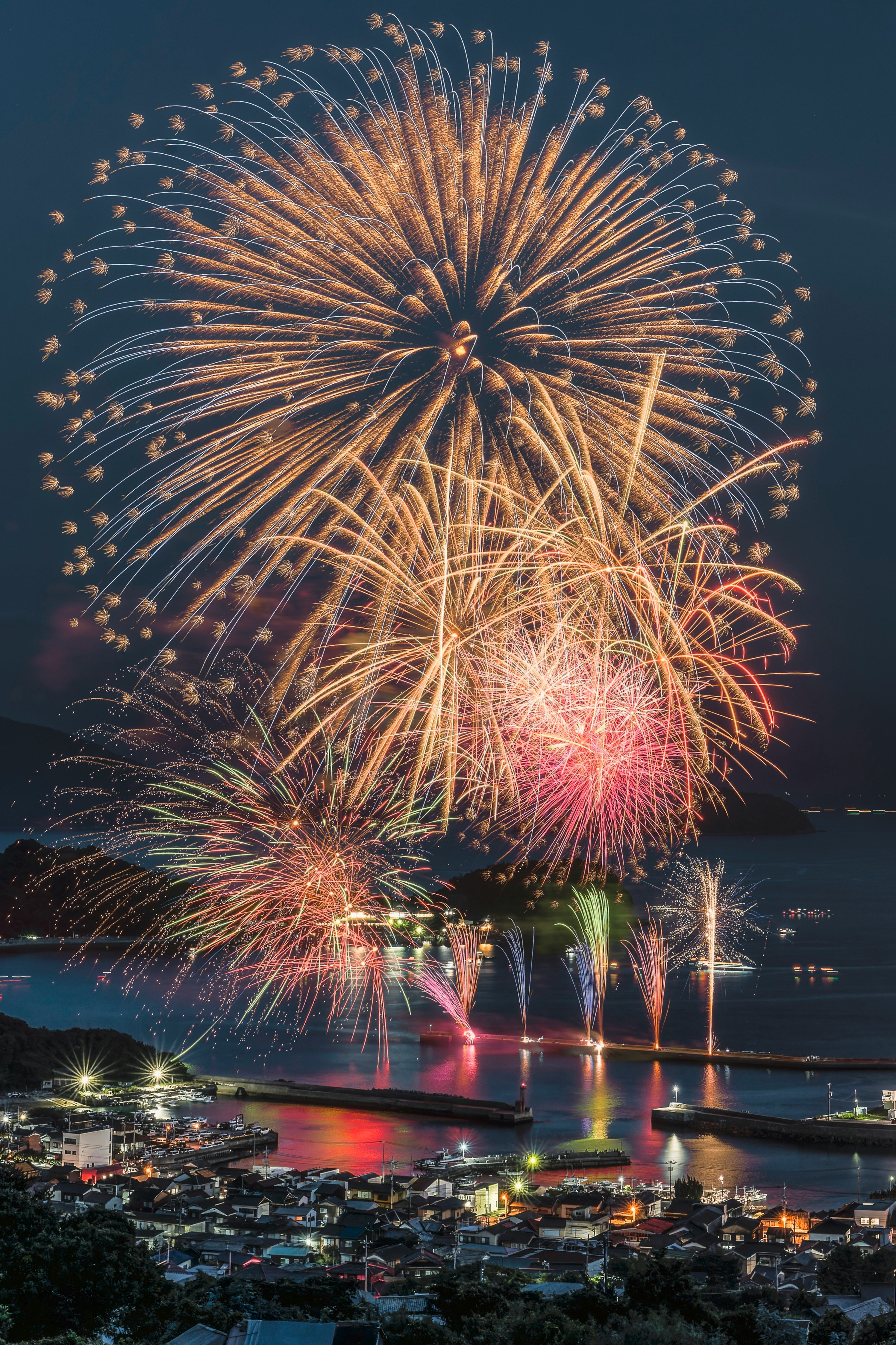 瀬戸内海の海上に打ち上がる花火と港の夜景