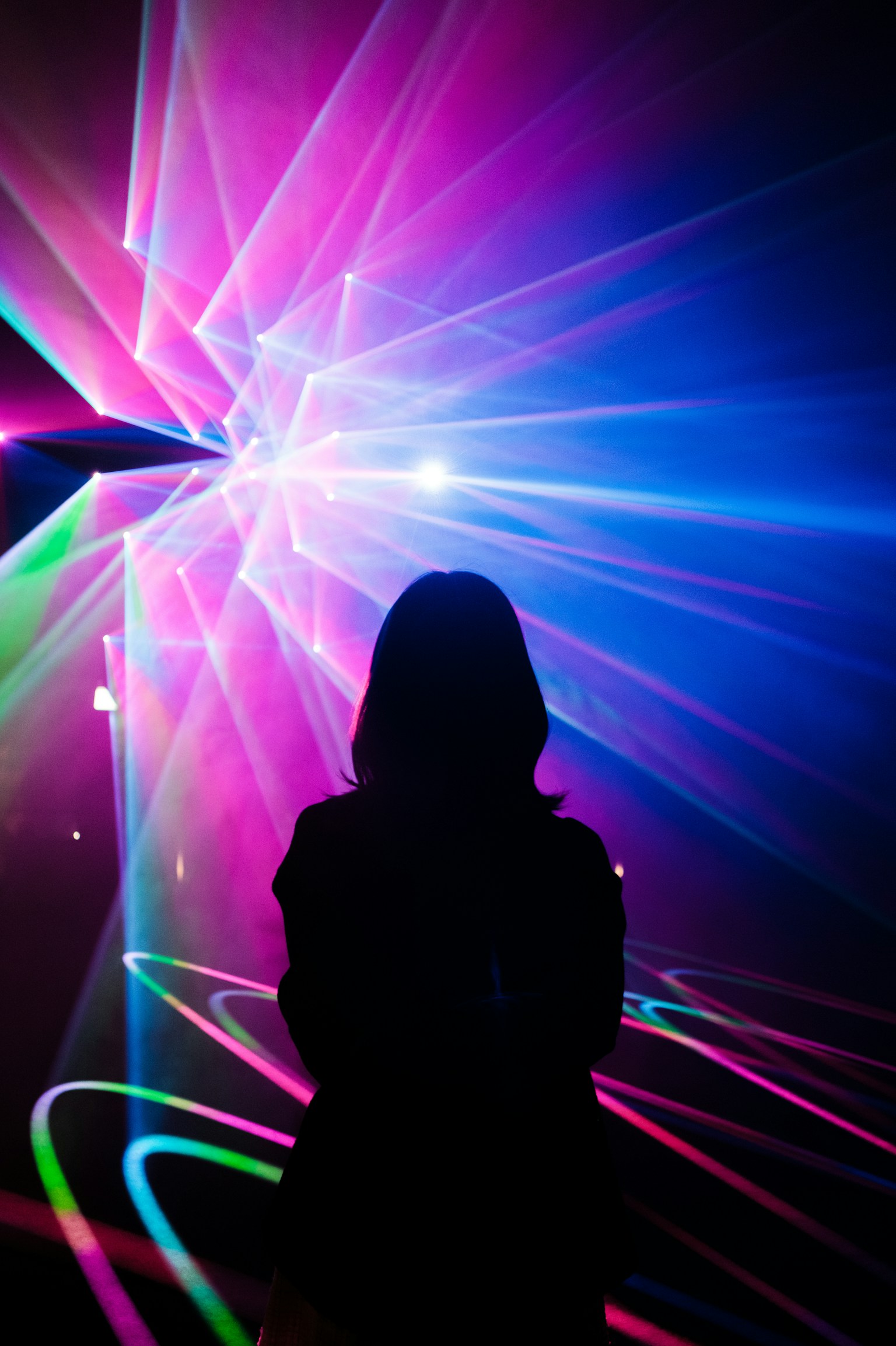 Silhouette of a person against colorful laser lights