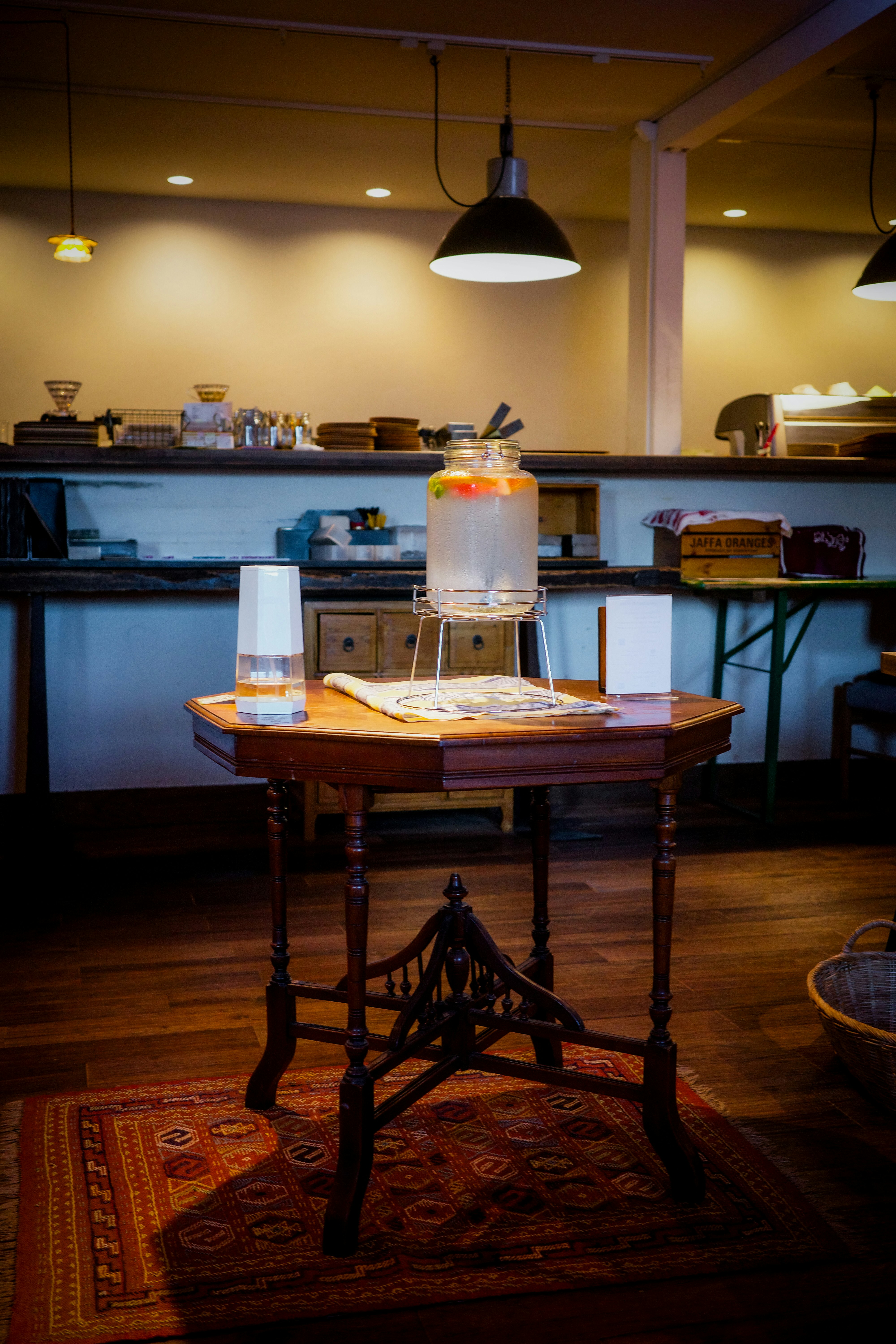 カフェ店内の木製テーブルとドリンクディスペンサーのある風景